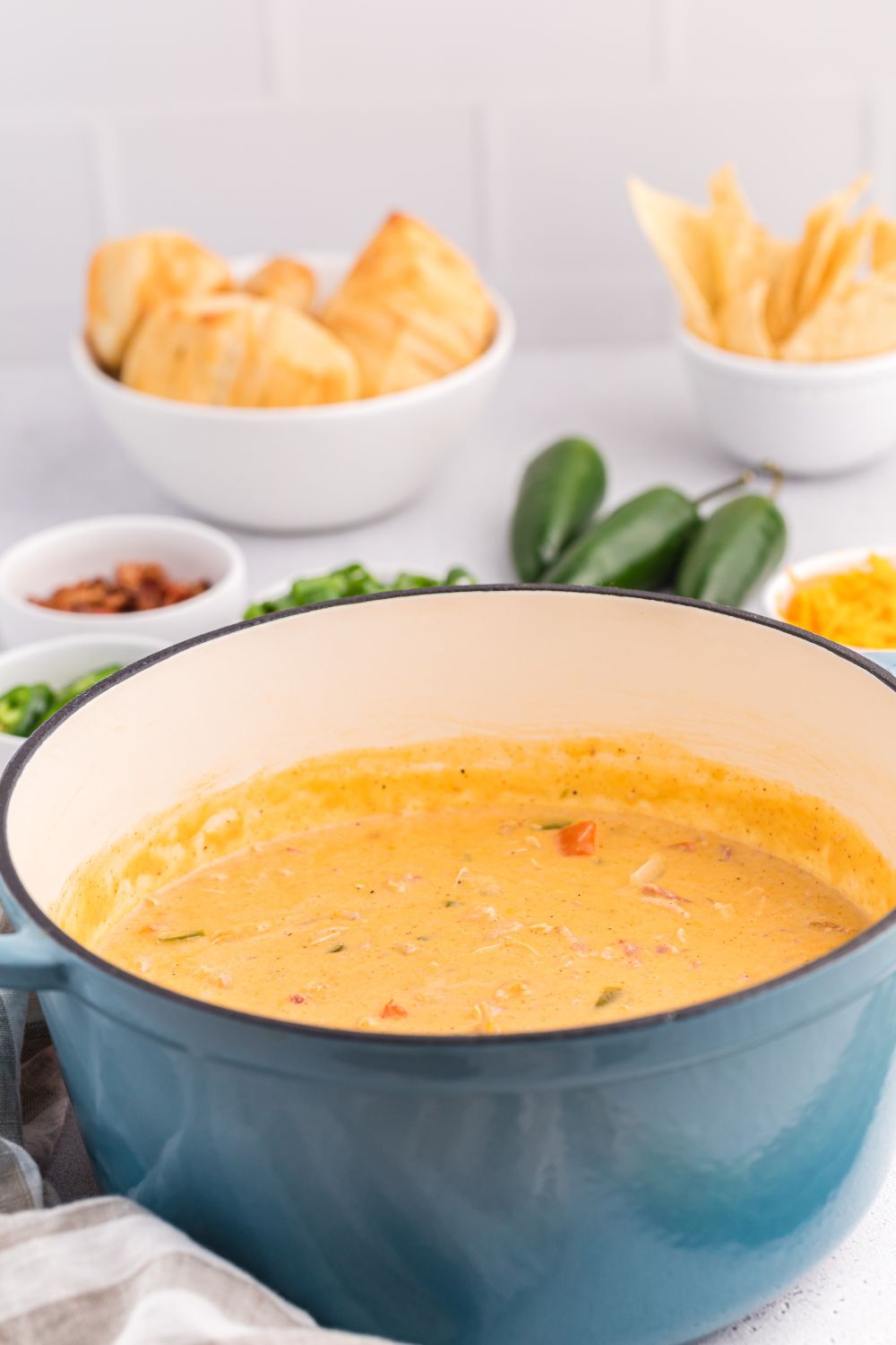 side view of a pot full of jalapeño popper crack chicken soup with chips behind it on the table