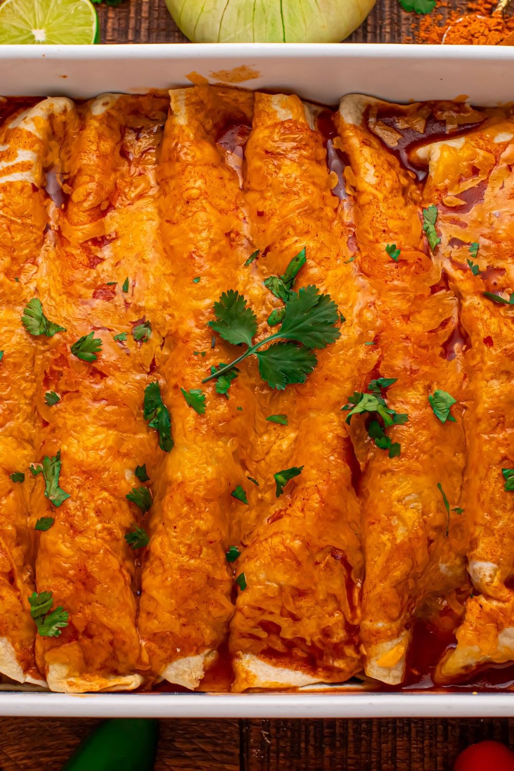 a casserole pan full of Steak Enchiladas on wooden table with chopped cilantro on top