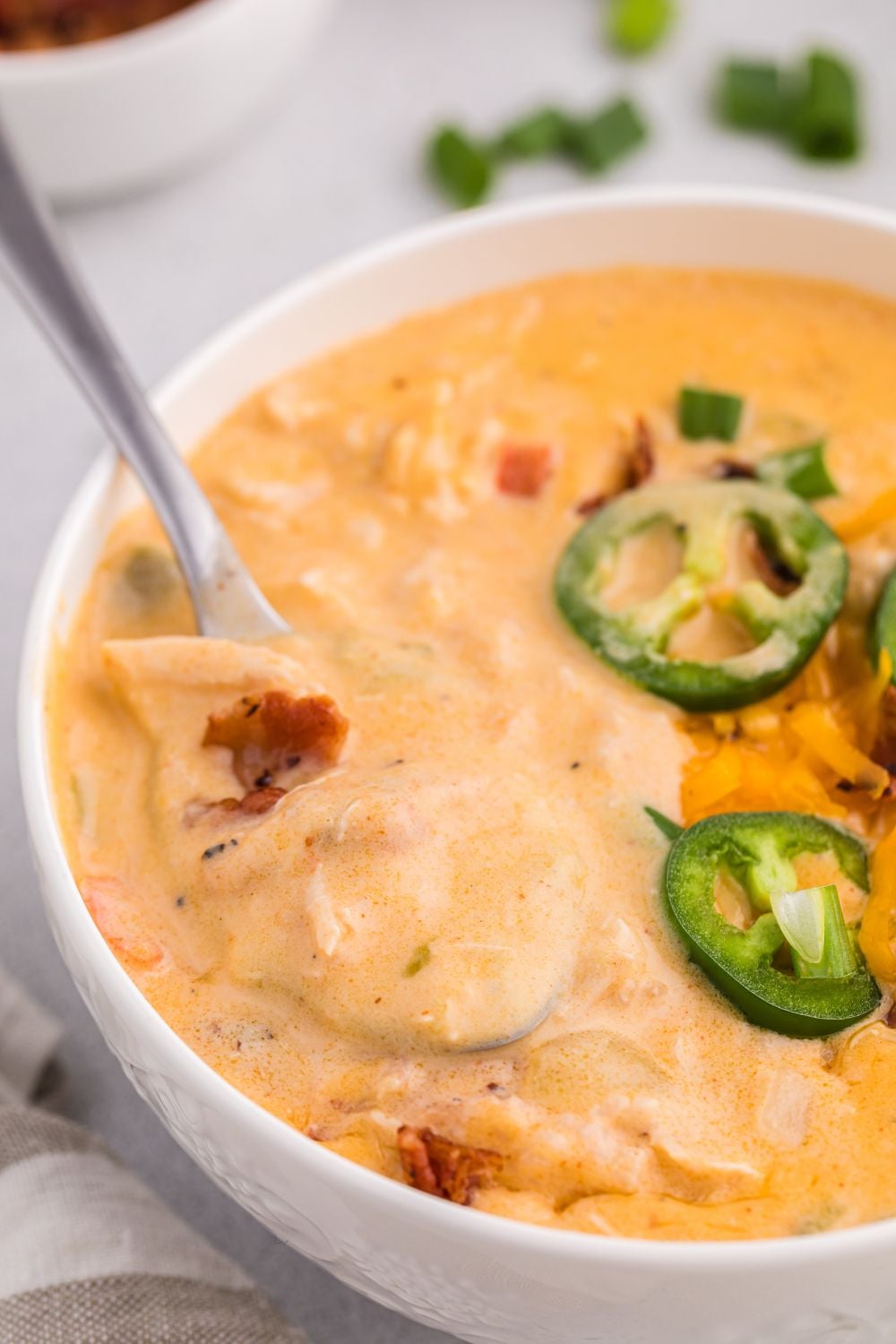jalapeño popper crack chicken soup in a white bowl topped with jalapeno pepper and bacons
