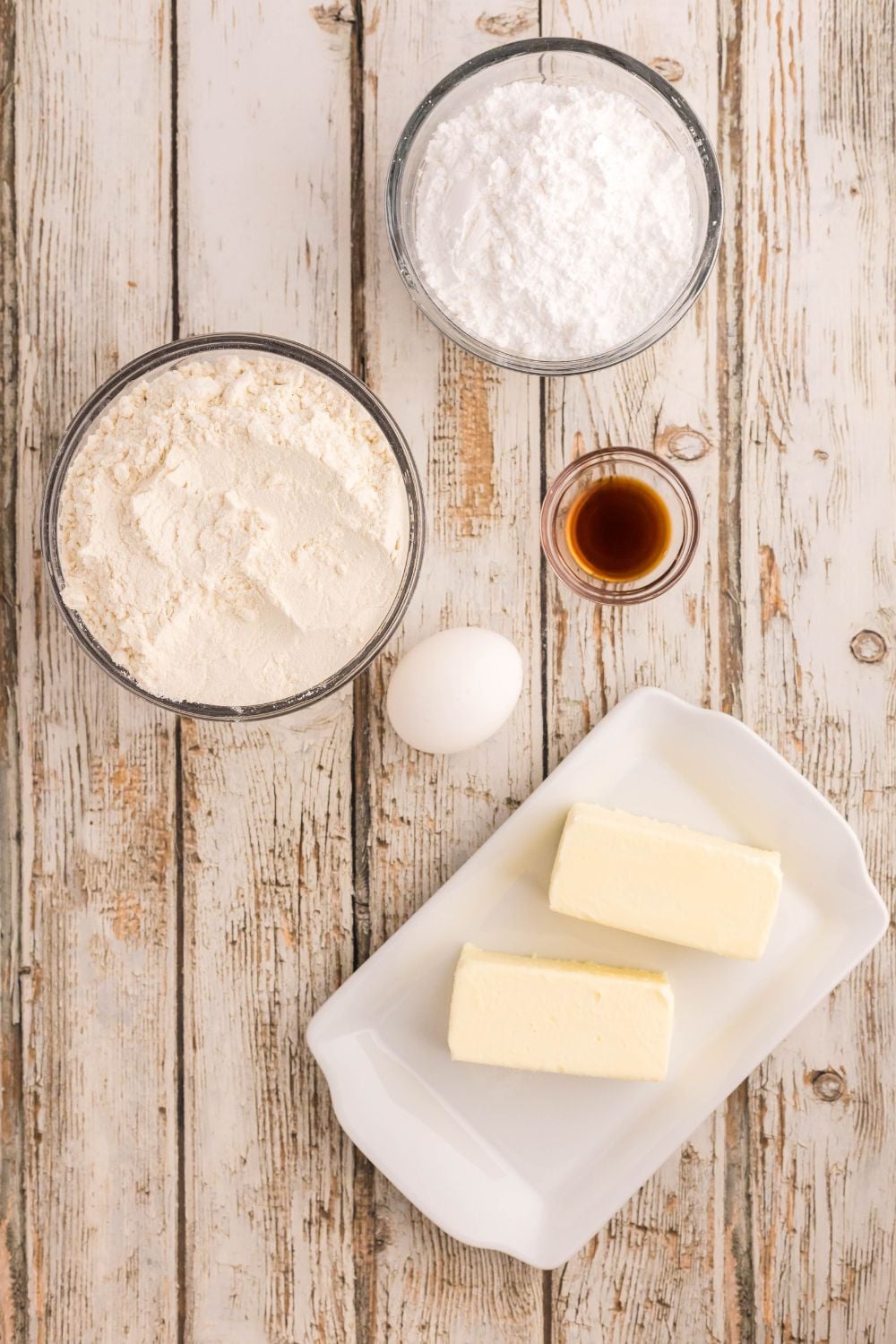 ingredients to make Decorated Sugar Cookies on a wooden table in single serve bowls