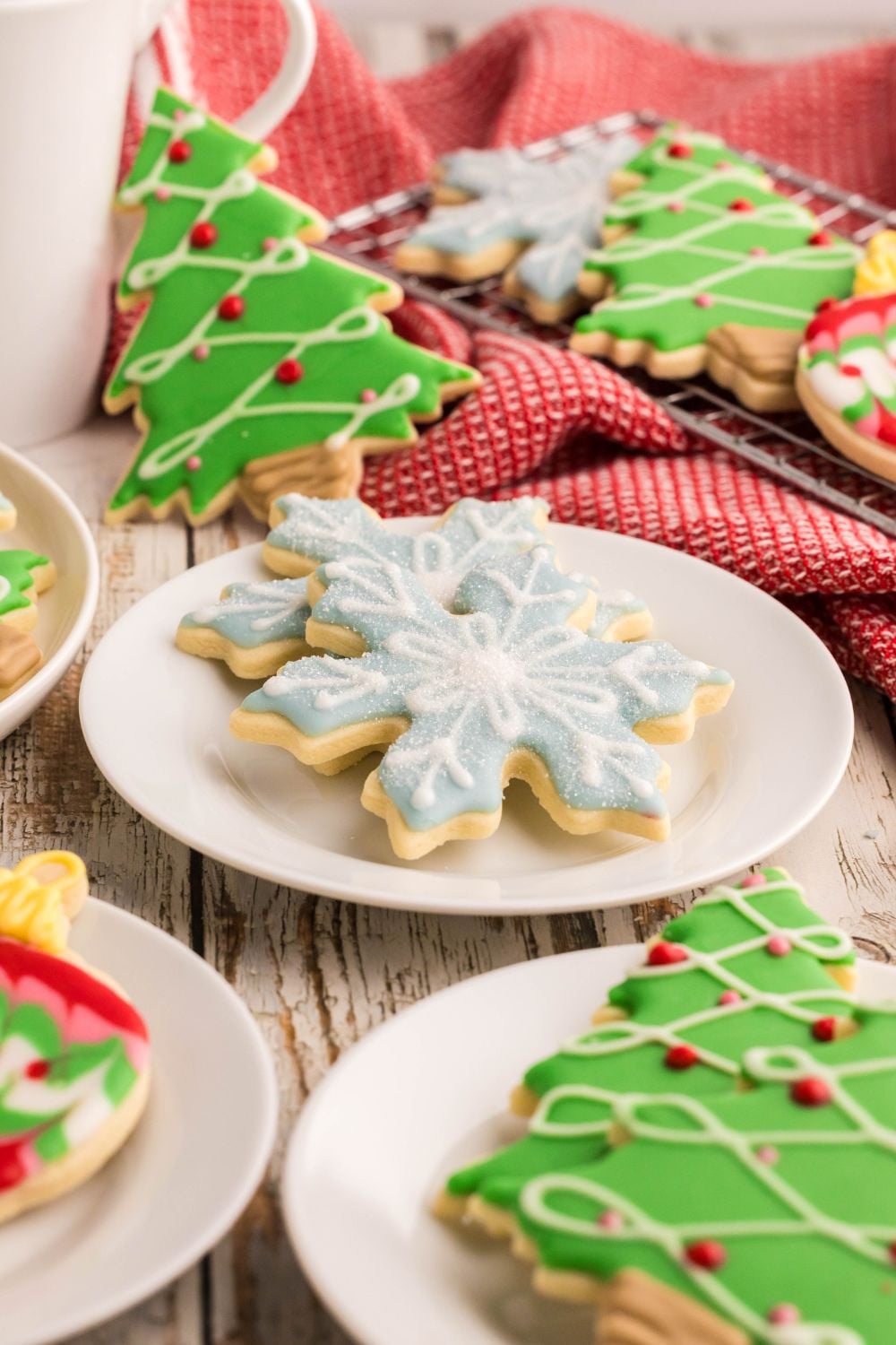 Christmas Decorated Sugar Cookies on small plates on the table with a tray full of more cookies to the side
