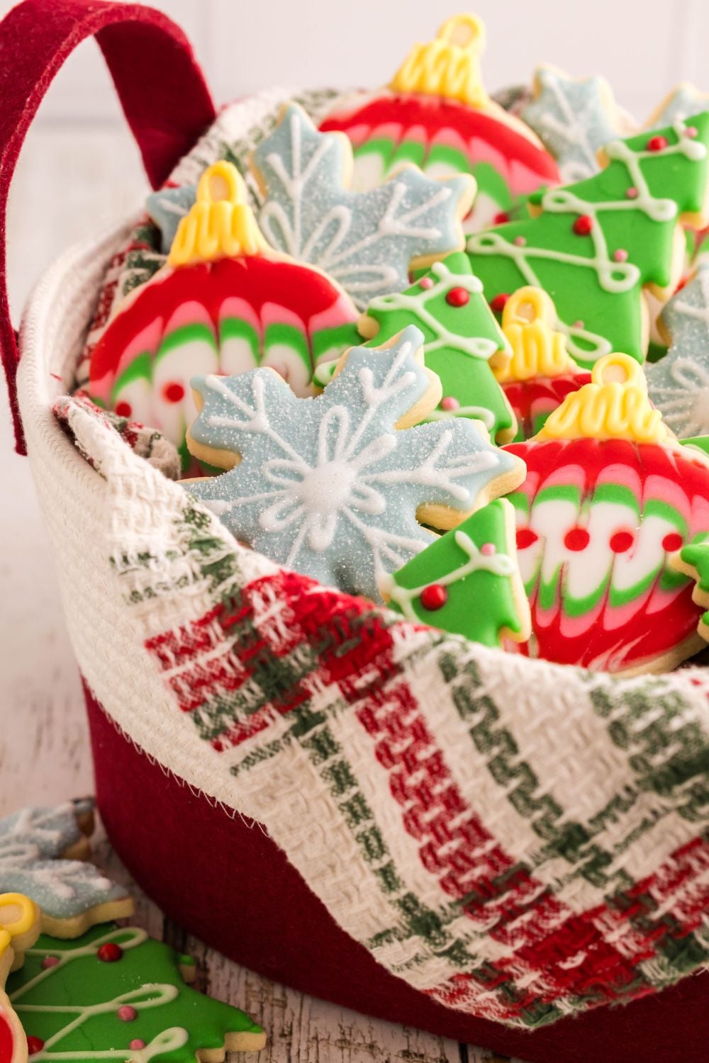 a metal tin with a towel inside full of Christmas sugar cookies with royal icing on it
