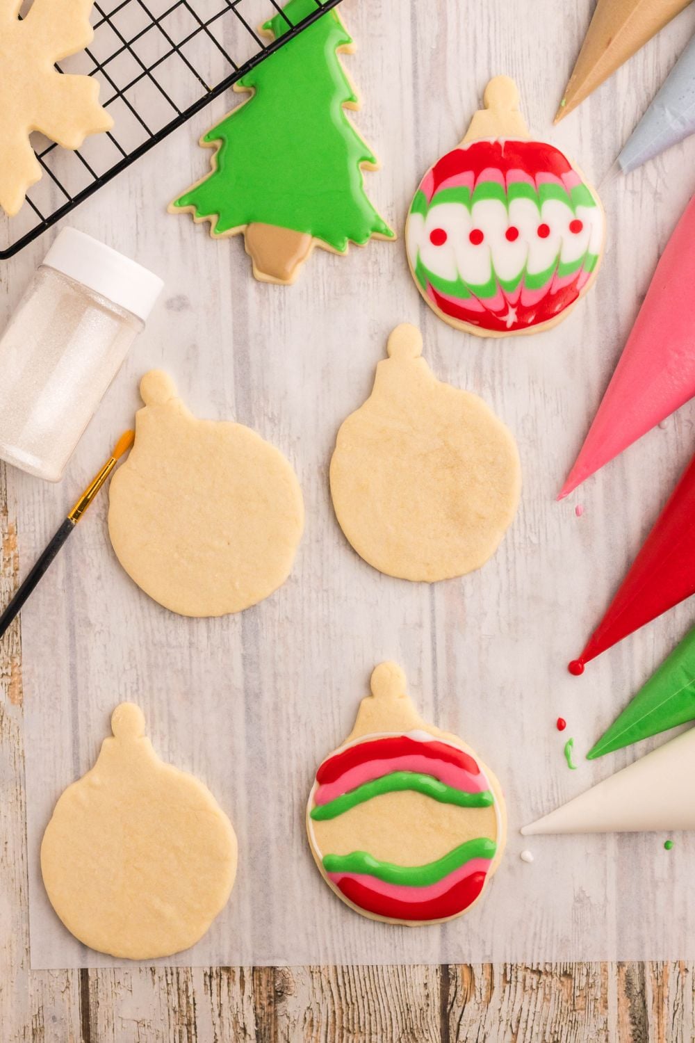 Christmas ornaments on table being piped with royal icing to decorate them like ornaments for a Christmas tree