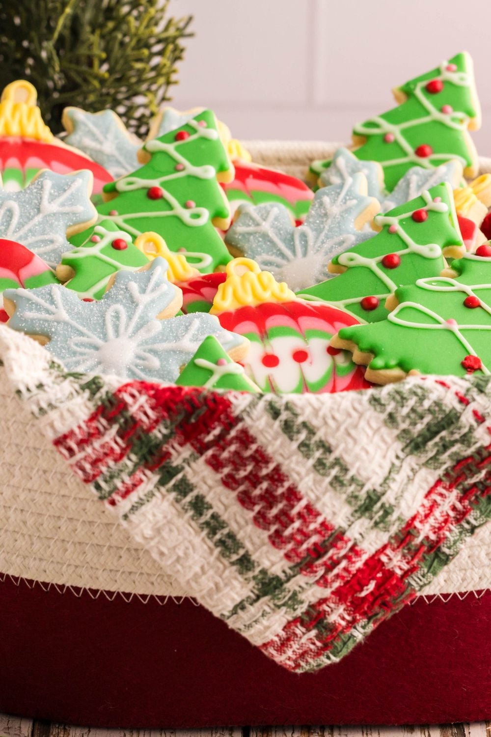 Decorated Sugar Cookies that are Christmas themed in a woven basket on the table