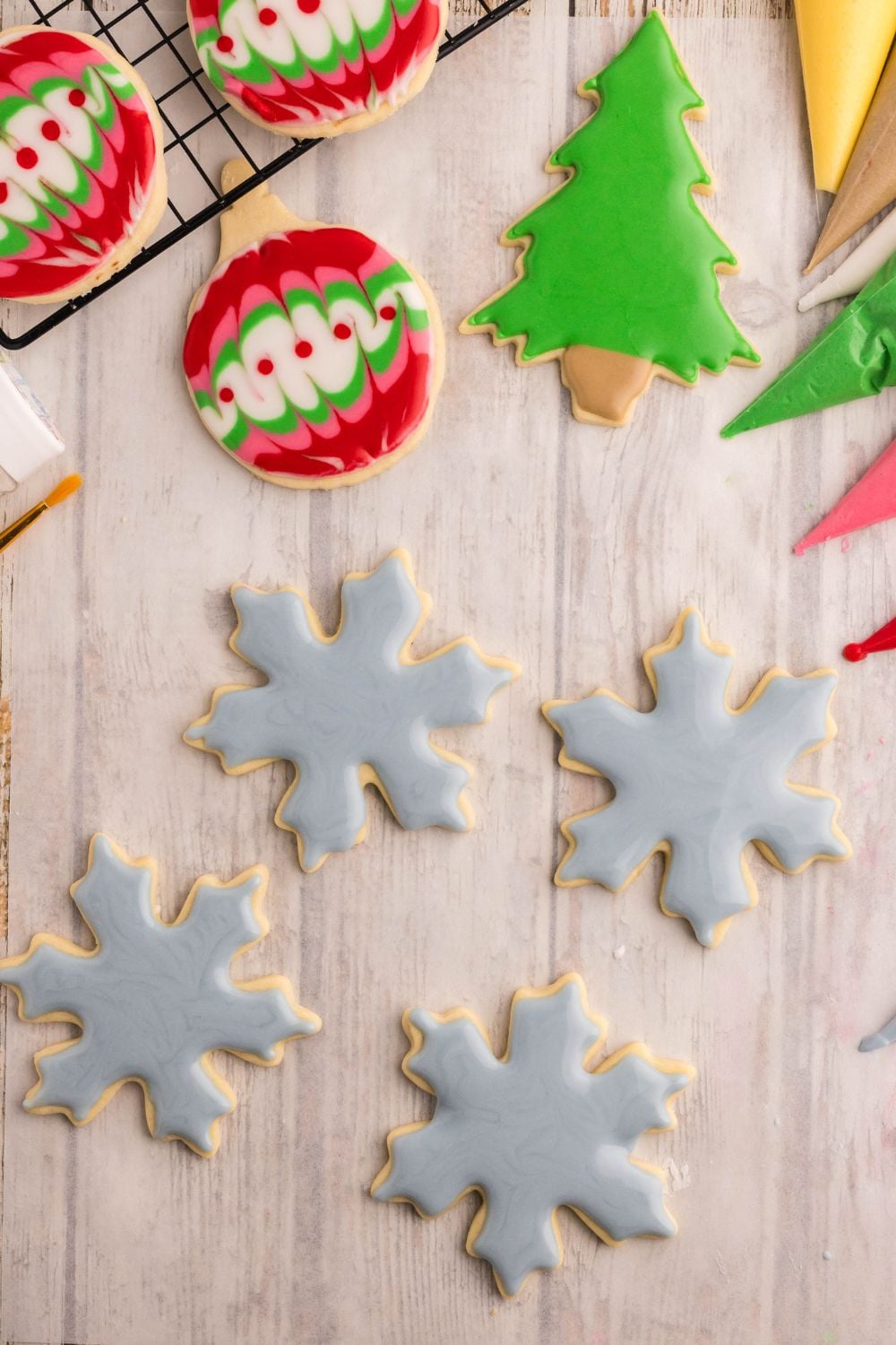 Decorated Sugar Cookies spread around table all shaped like Christmas ornaments and snowflakes