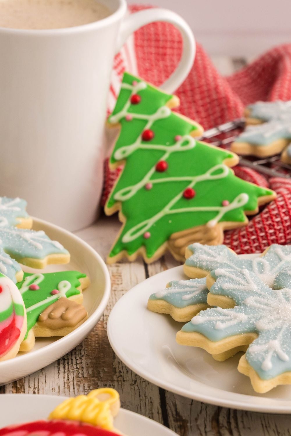 table decorated for Christmas with a coffee cup and Decorated Sugar Cookies scattered around the table