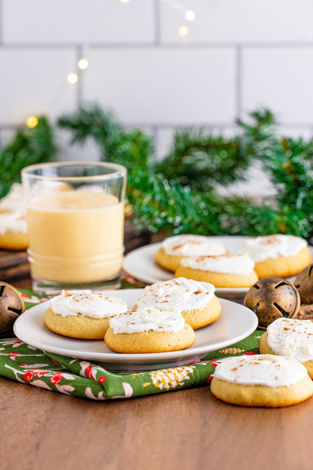 Christmas themed table with plates of eggnog cookies and a glass of eggnog to side