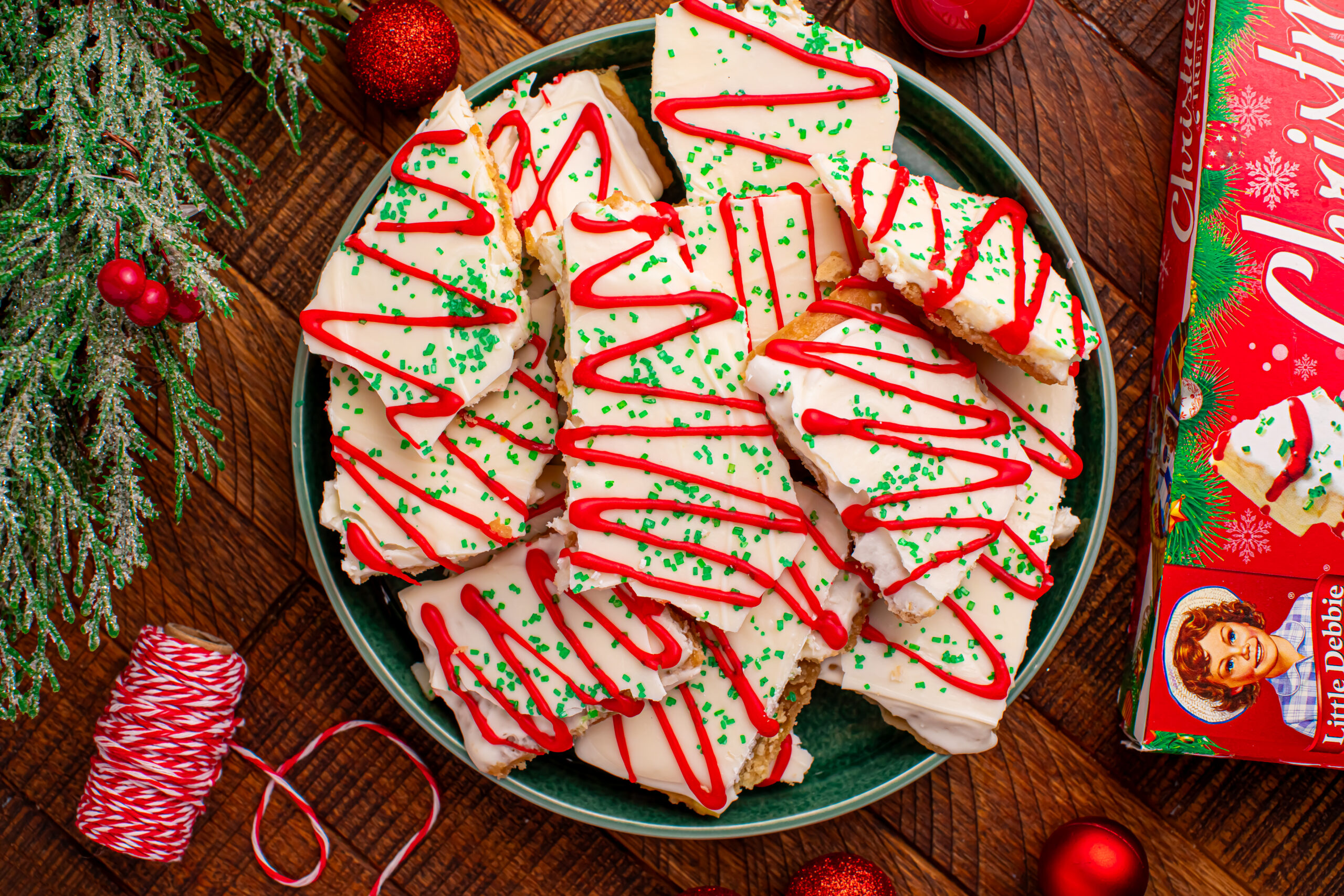 Overhead shot of the Christmas Tree Crack piled on a green serving platter on a dark wood table surrounded by christmas decorations