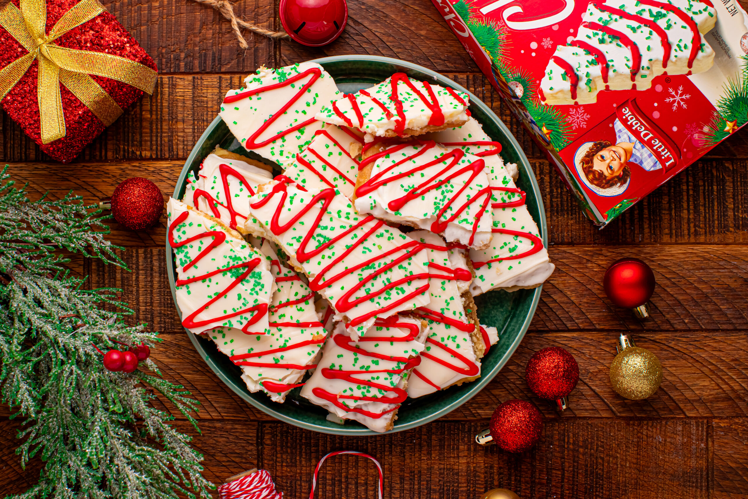 Overhead photo of Christmas Tree Crack piled on a green serving platter on a dark wood table surrounded by christmas decorations