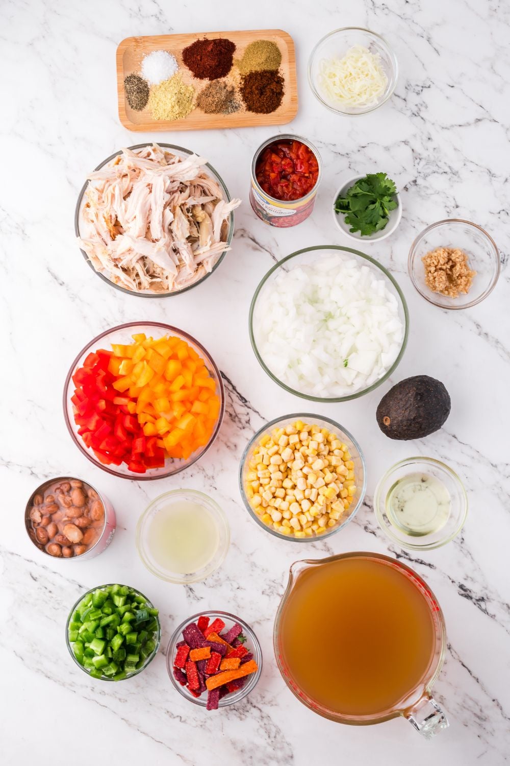 all the ingredients for Southwestern Chicken Soup in single serve bowls on a marble counter
