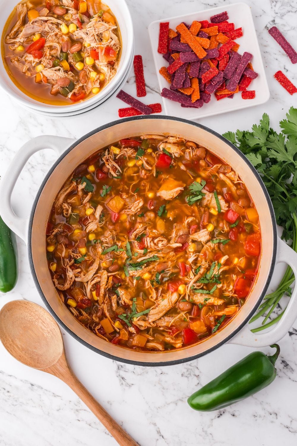 a white pot on table with southwestern soup in a pot and another small bowl to the side and chips to the side