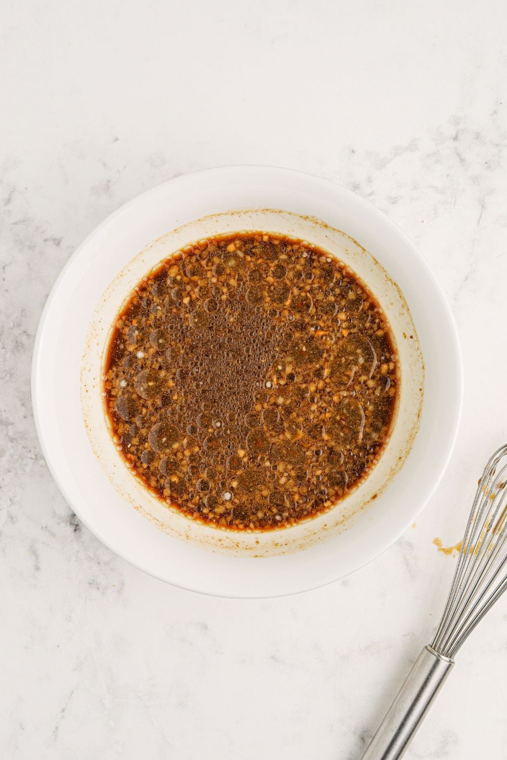 bourbon sauce in a white bowl sitting on a marble counter