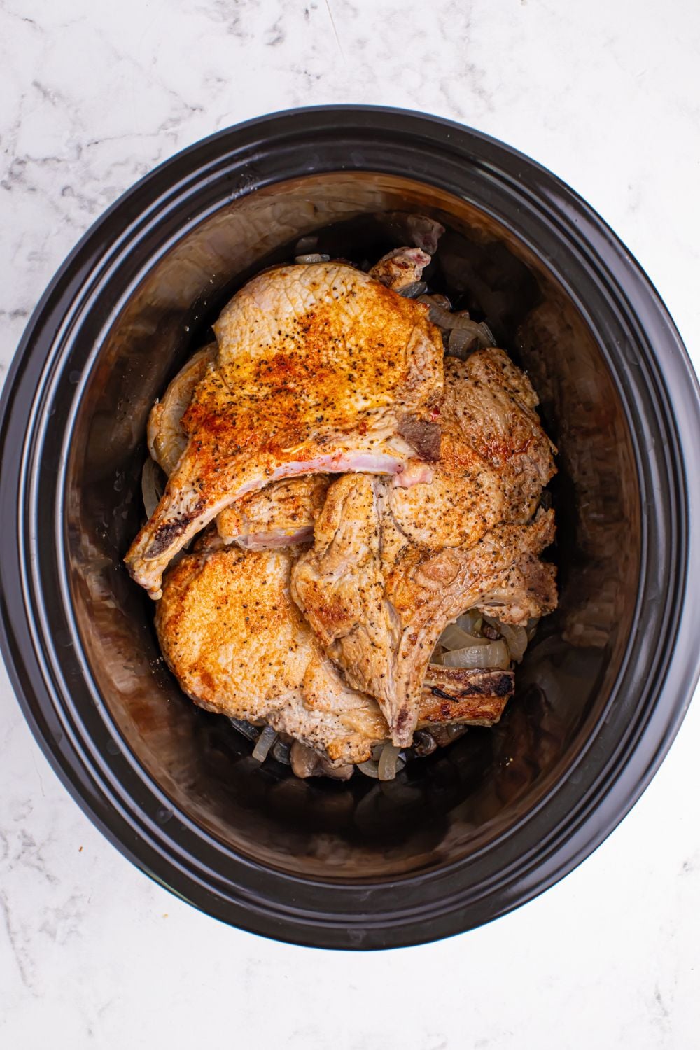 crockpot on table with fried pork chops in crockpot 