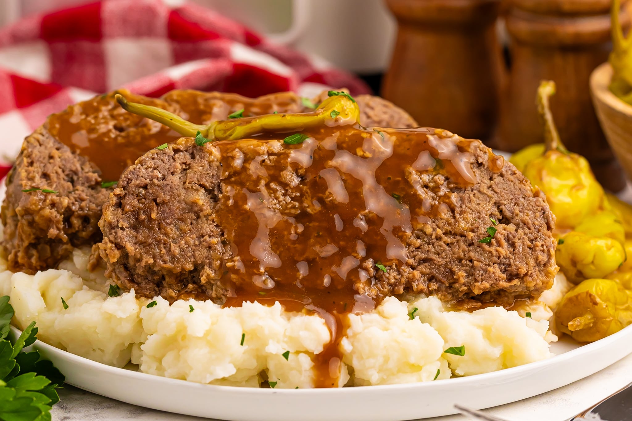 Crockpot Mississippi Meatloaf on a white plate on top of fluffy mashed potatoes