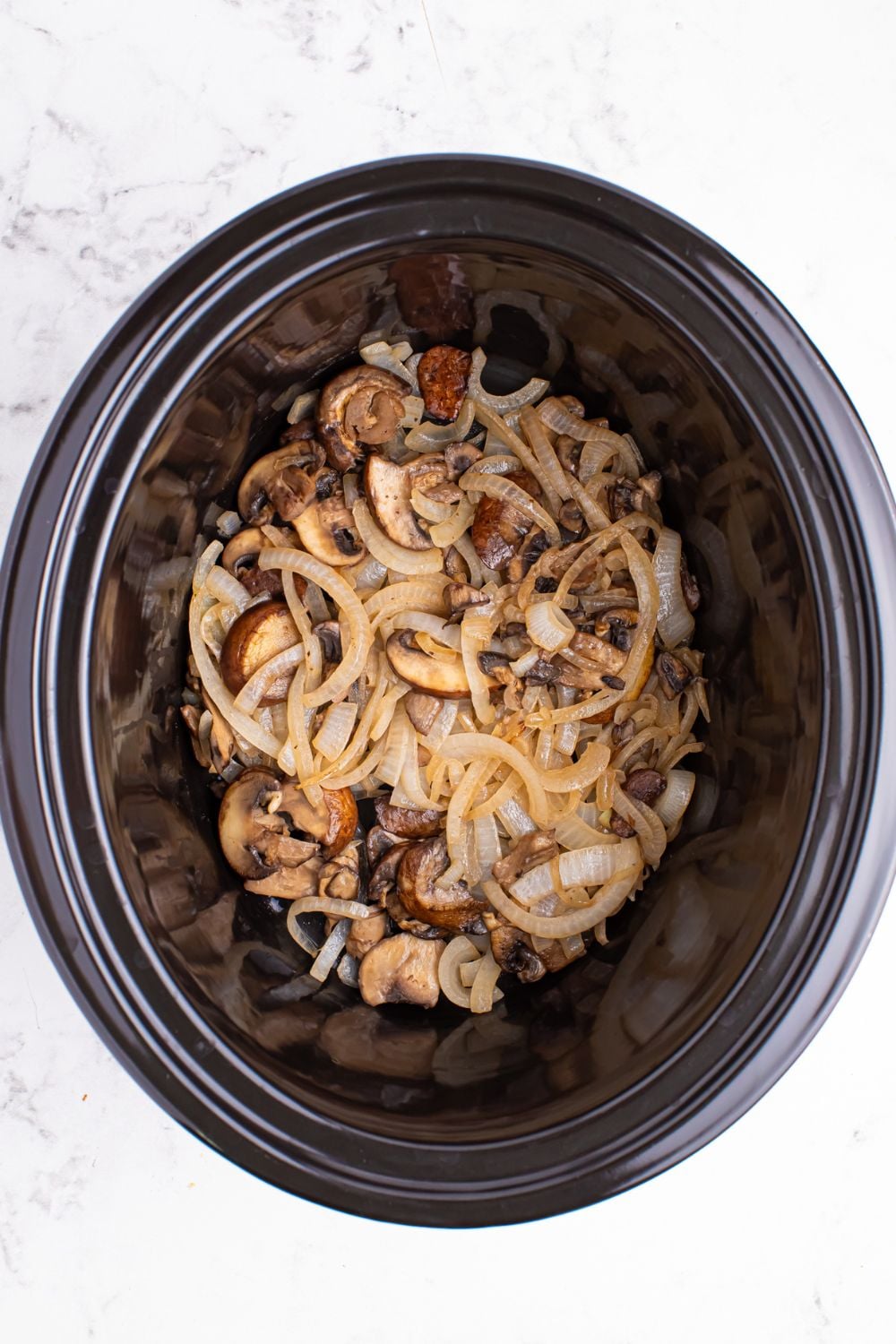seared mushrooms and onions in a crockpot 