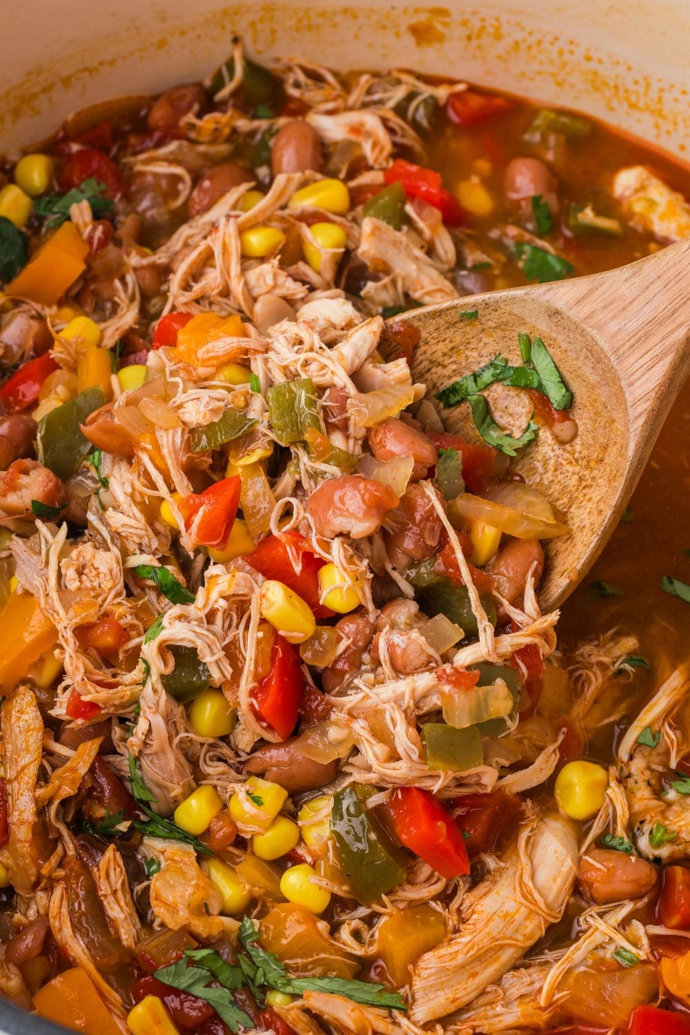 Southwestern Chicken Soup in a pot with a wooden spoon scooping up some of the soup