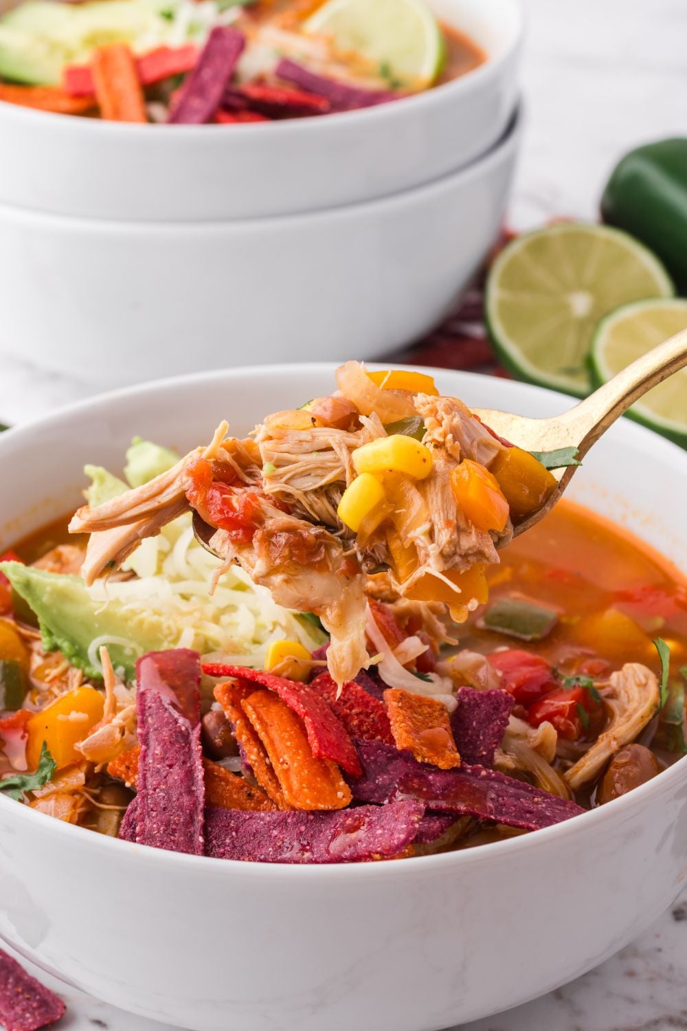 spoon lifting up some of the Southwestern Chicken Soup in a white bowl on the table