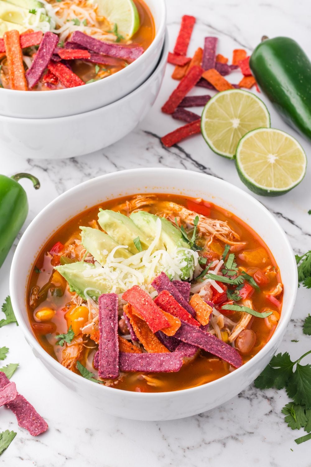 Southwestern Chicken Soup in a white bowl on table with sliced limes and more bowls to the side