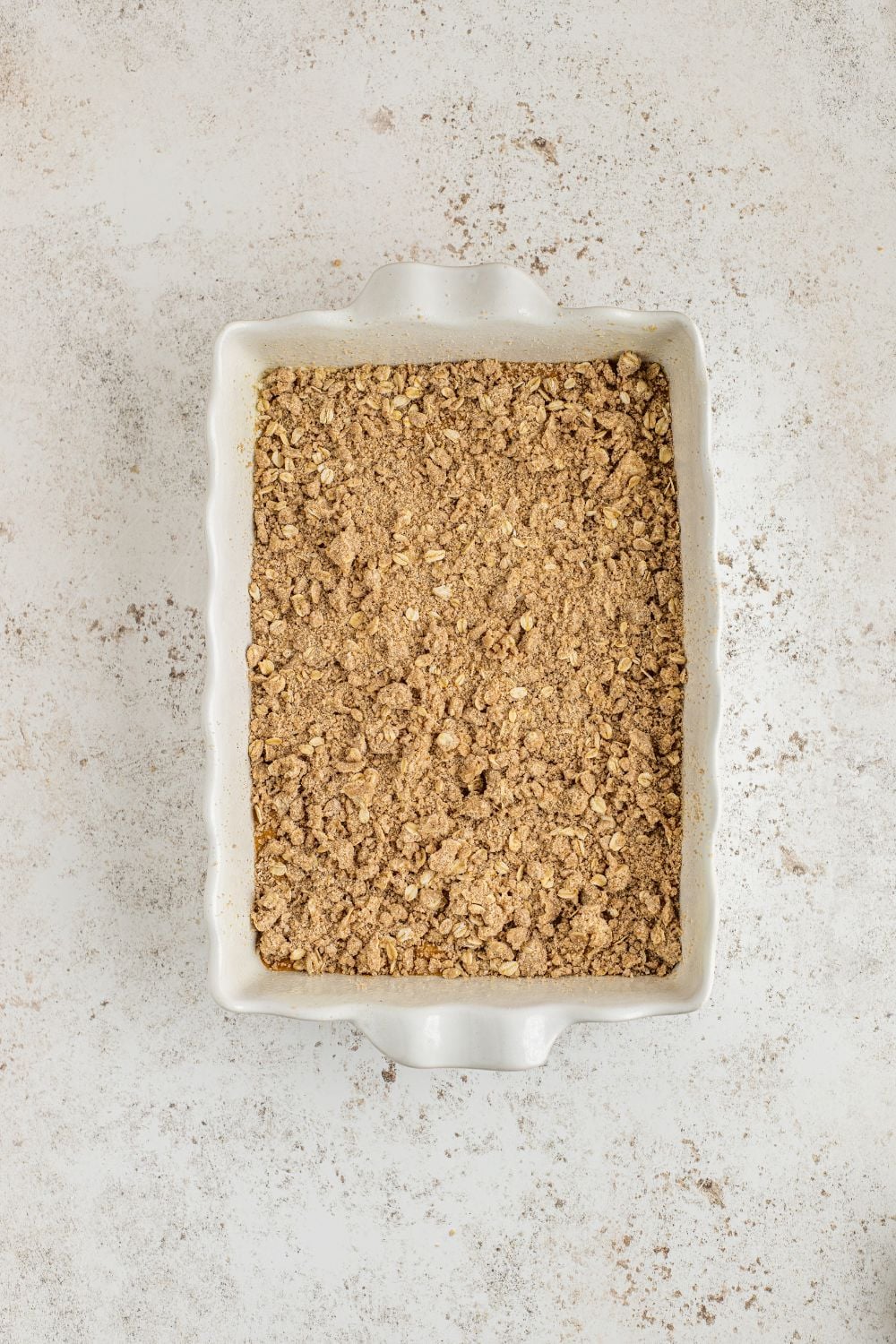 raw Homemade Pumpkin Crisp poured into a pan on the table with crumble on top