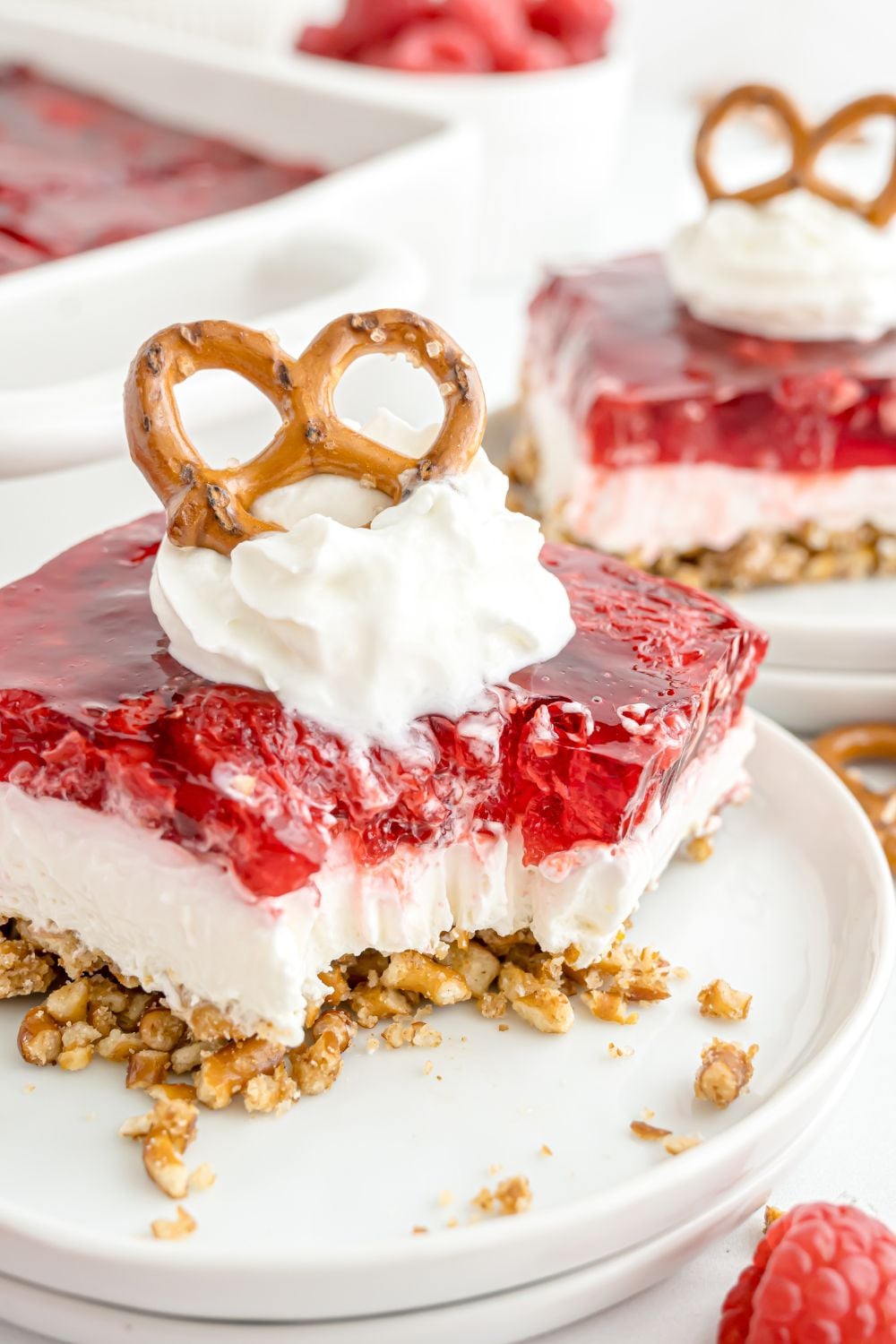 a slice of Raspberry Pretzel Salad placed on a plate with a bite taken out of it