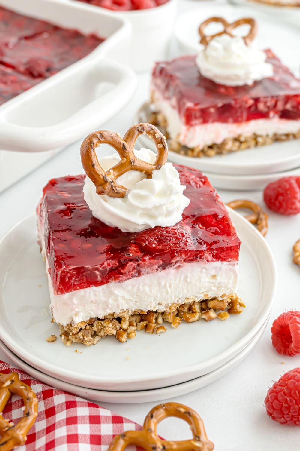 Raspberry Pretzel Salad sliced and placed on the table with whipped cream and pretzels on top of each dessert