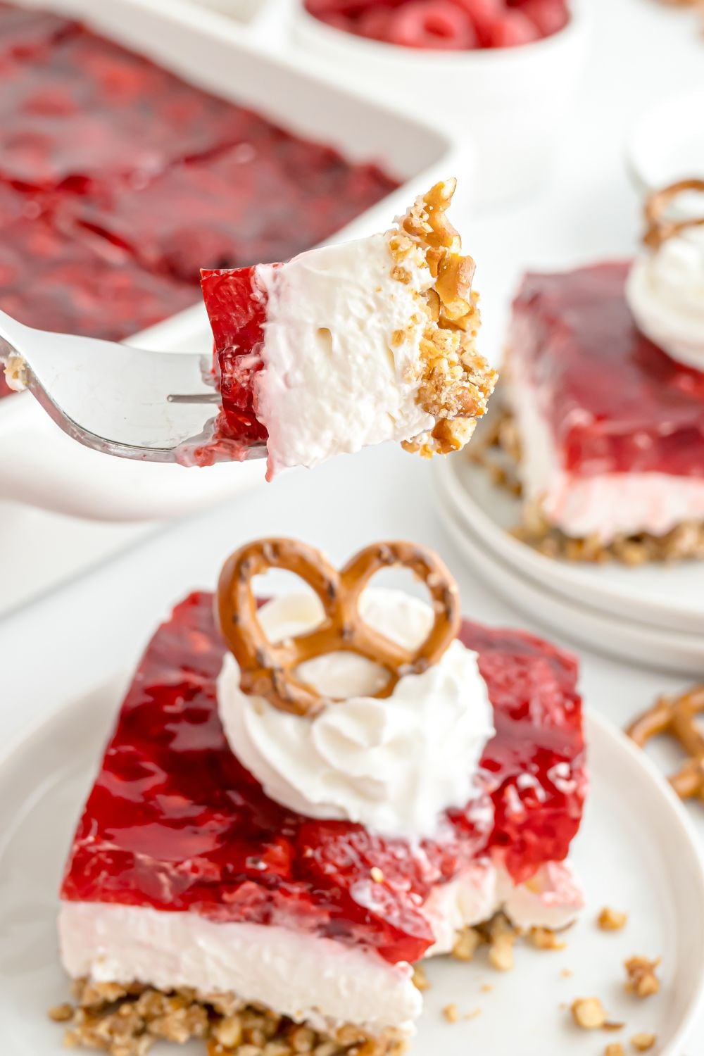Raspberry Pretzel Salad placed on plates and then the casserole dish behind it on the table