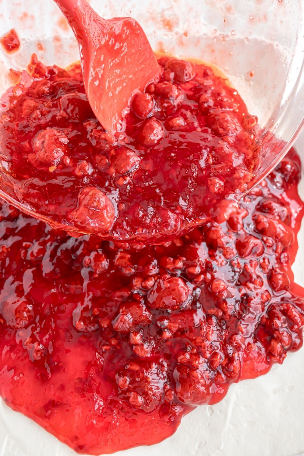 raspberry mixture pouring over the pretzel salad mixture