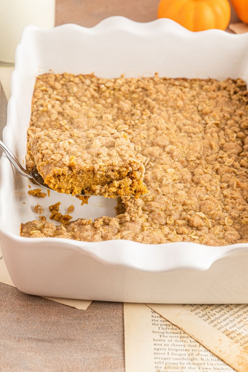 Homemade Pumpkin Crisp in a white casserole pan with a piece scooped out of the pan