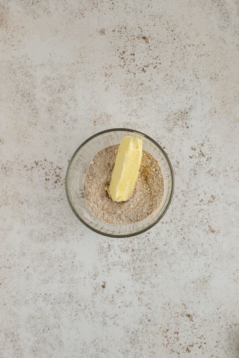 butter and dry ingredients for making Homemade Pumpkin Crisp in a glass bowl on the marble counter