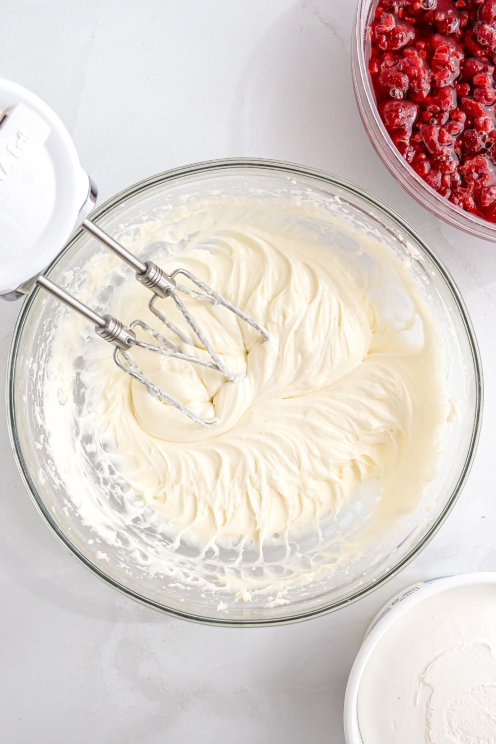 glass bowl mixing up the cream cheese mixture for a raspberry pretzel salad