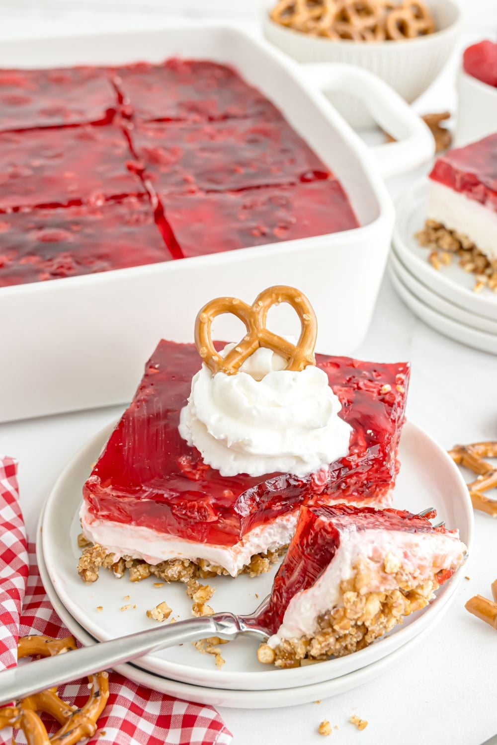 Raspberry Pretzel Salad on a plate with a bite on a fork in front of plate with the dish full of salad