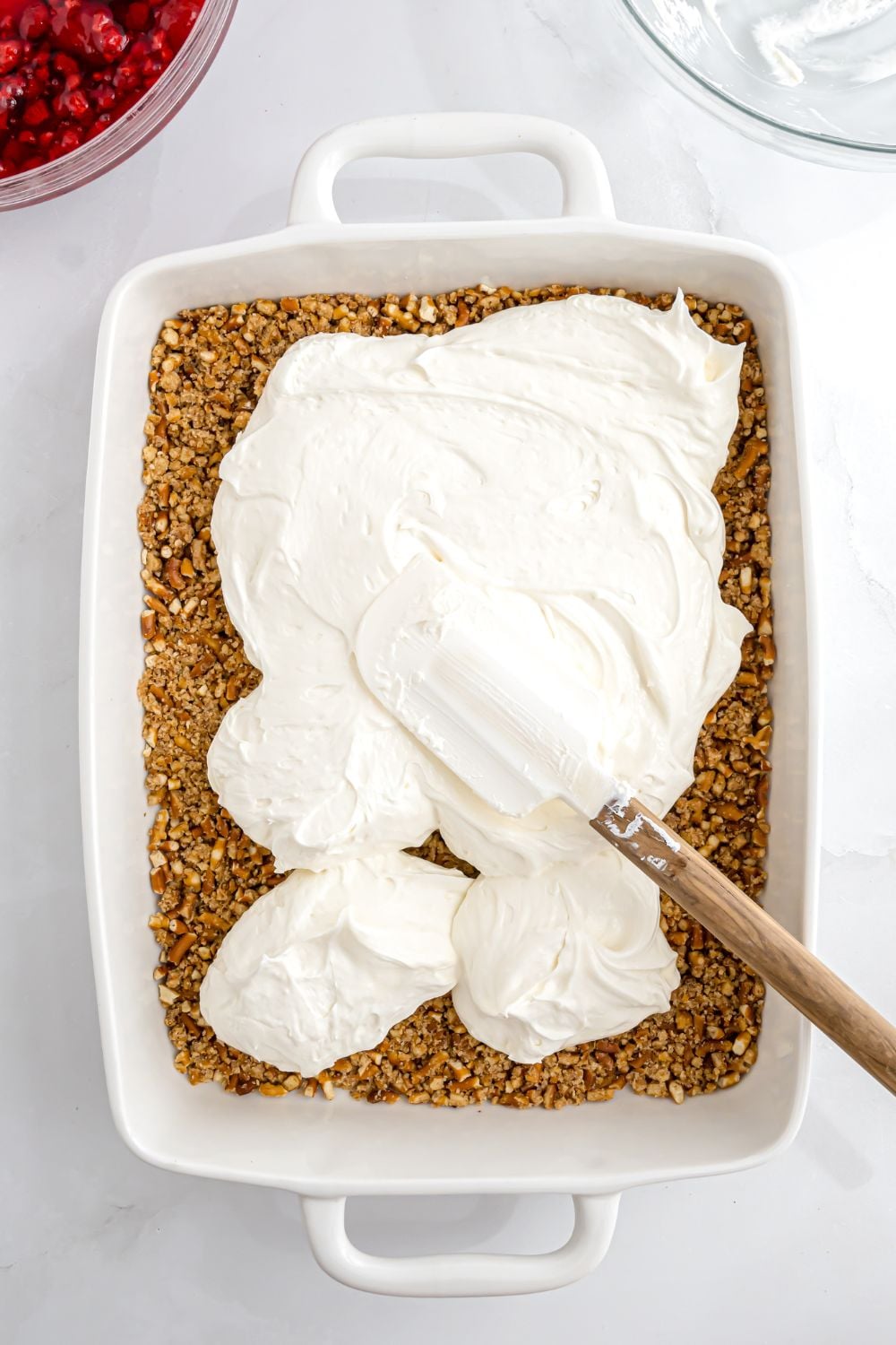 whipped mixture being spread over pretzel crust for a raspberry pretzel salad