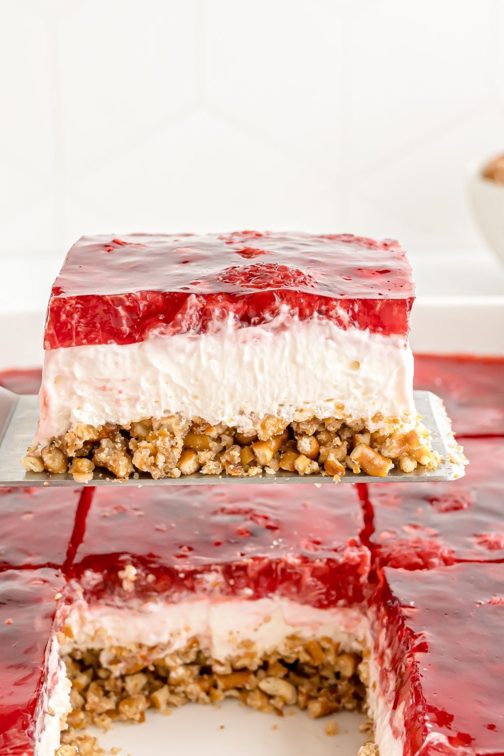 slice of pretzel salad being lifted out of the casserole pan with the rest of the dessert