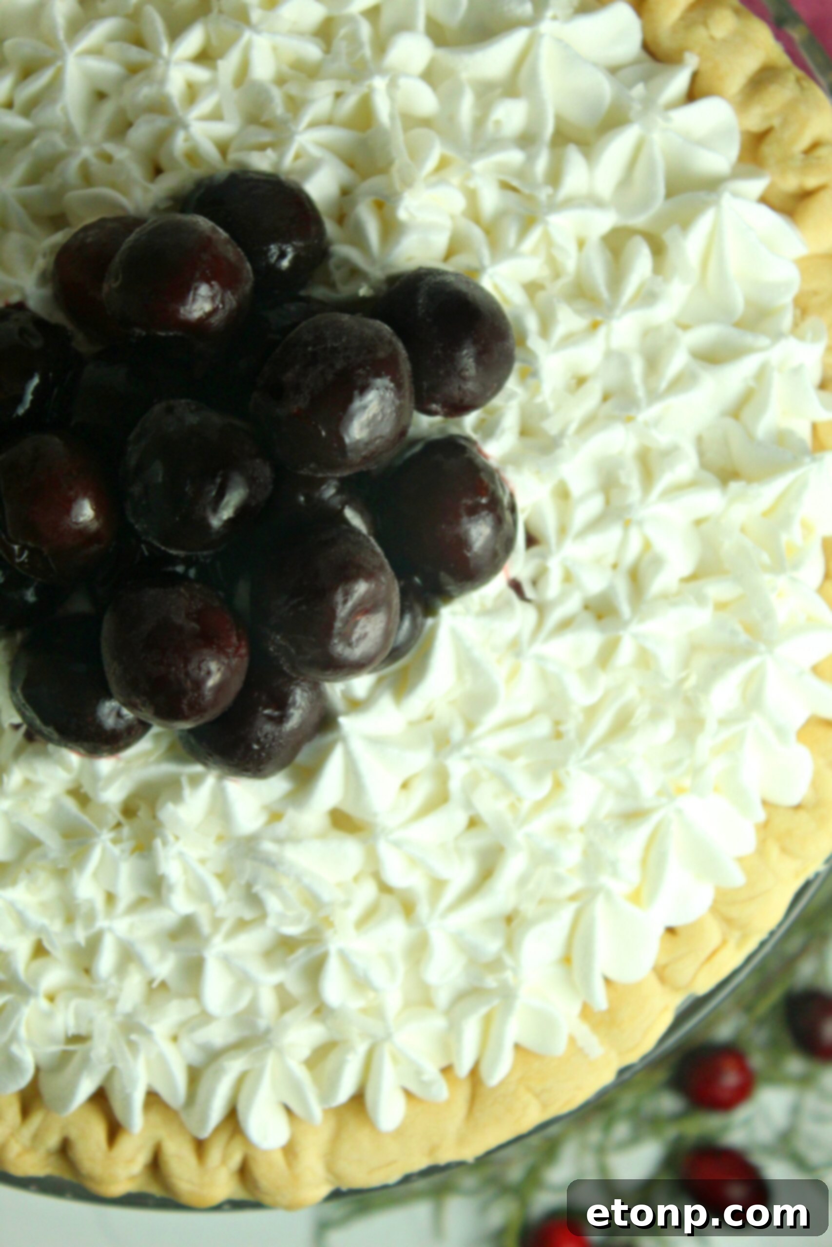 A vibrant close-up of the White Christmas Pie, beautifully garnished with fresh, juicy cherries, highlighting the bright red against the white coconut-infused filling. Other berry options are also discussed.