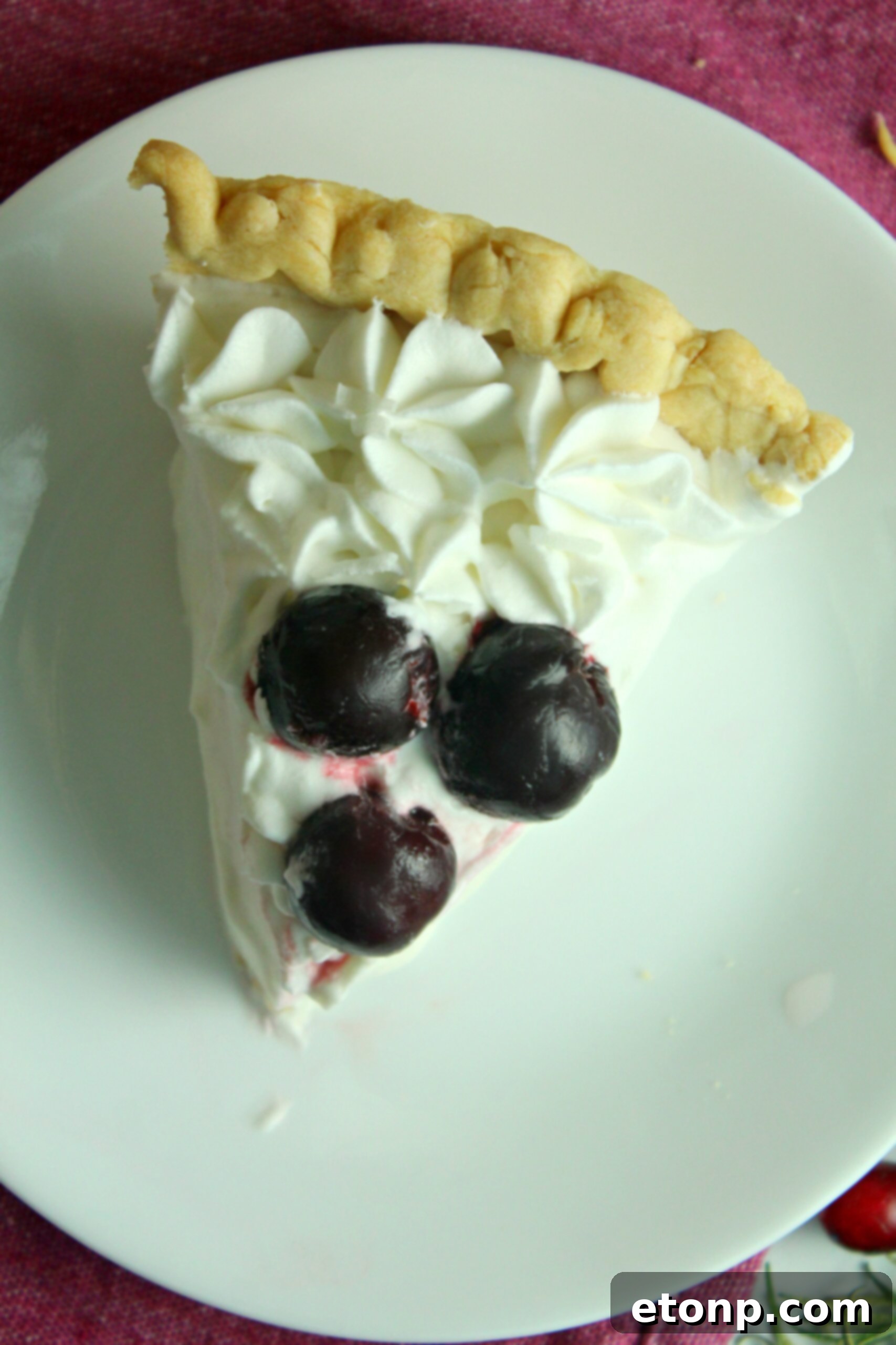 A top-down view of the White Christmas Pie, showcasing the elegantly piped whipped cream topping and sprinkled coconut, making it a beautiful centerpiece for a festive table.