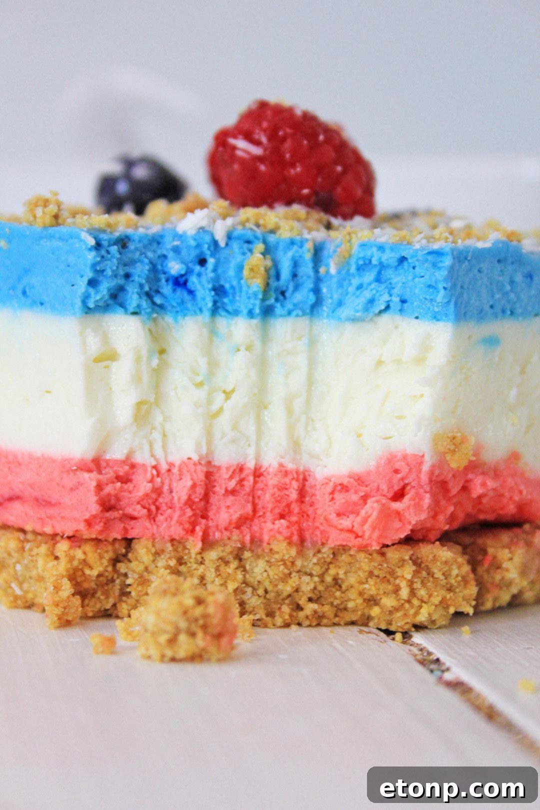 A slice of the layered berry cheesecake showing the individual colorful layers and crunchy crust.