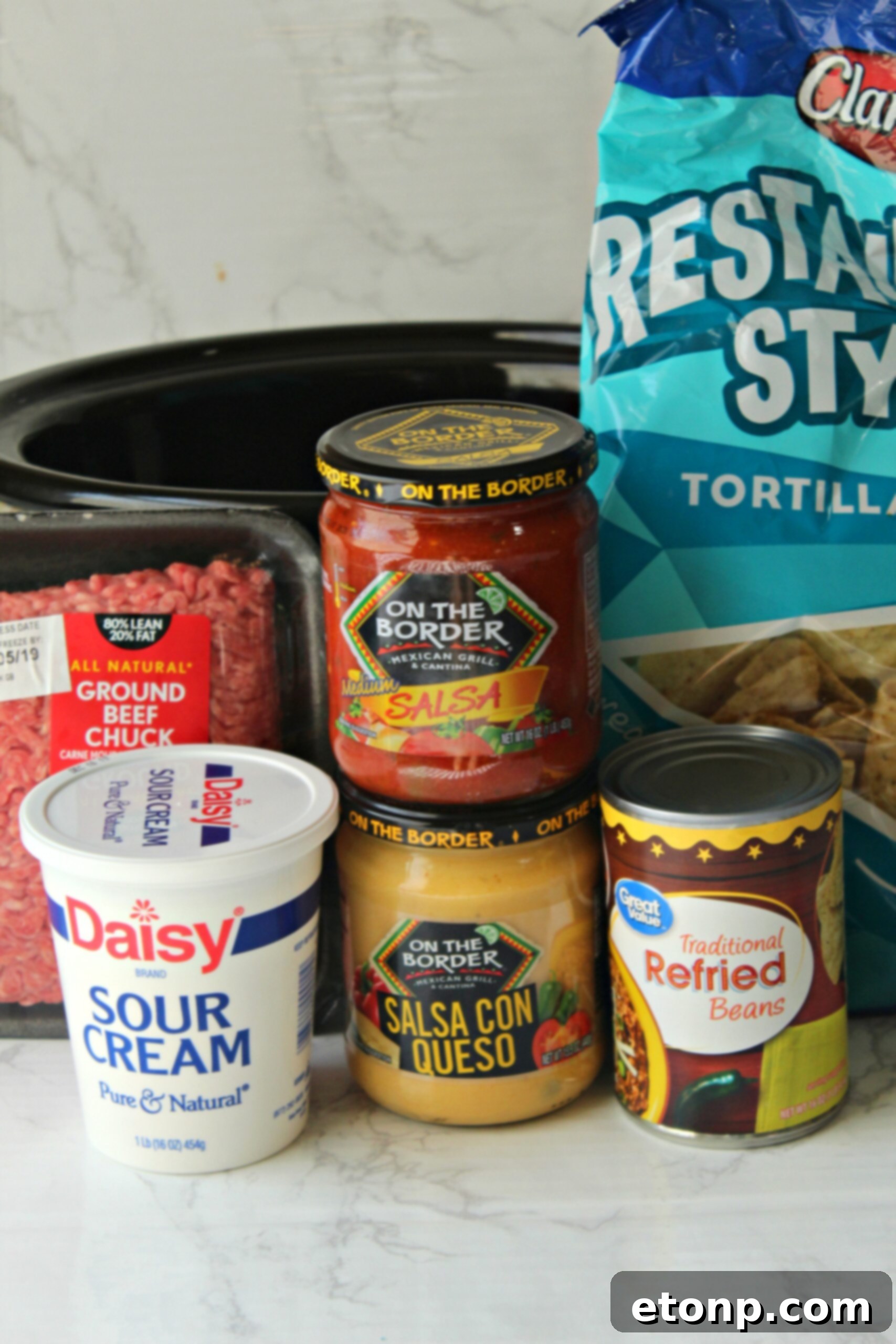 Warm and bubbly Slow Cooker Taco Dip with a serving spoon, ready for dipping