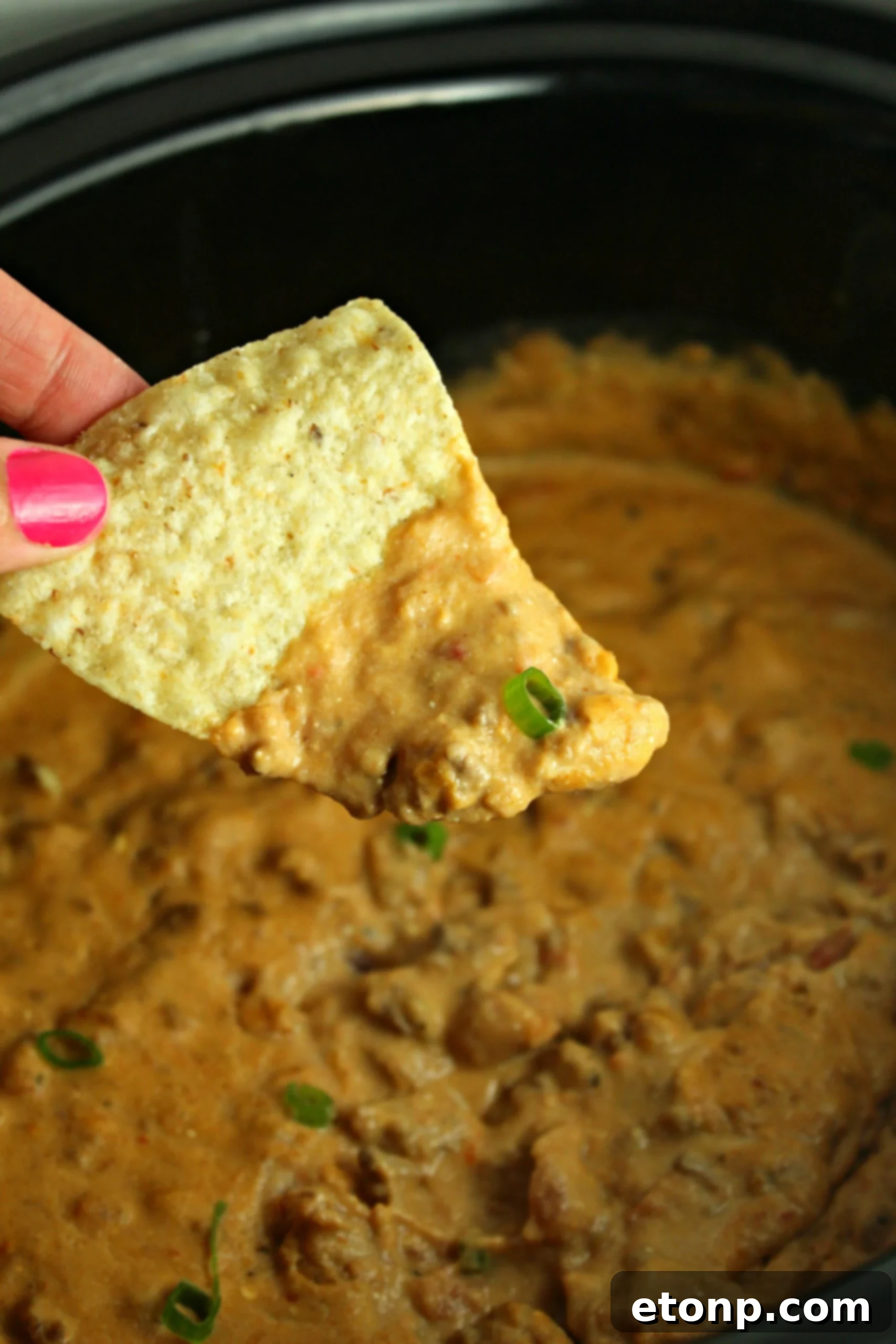 Close-up of bubbling Slow Cooker Taco Dip in a crock pot, topped with fresh cilantro