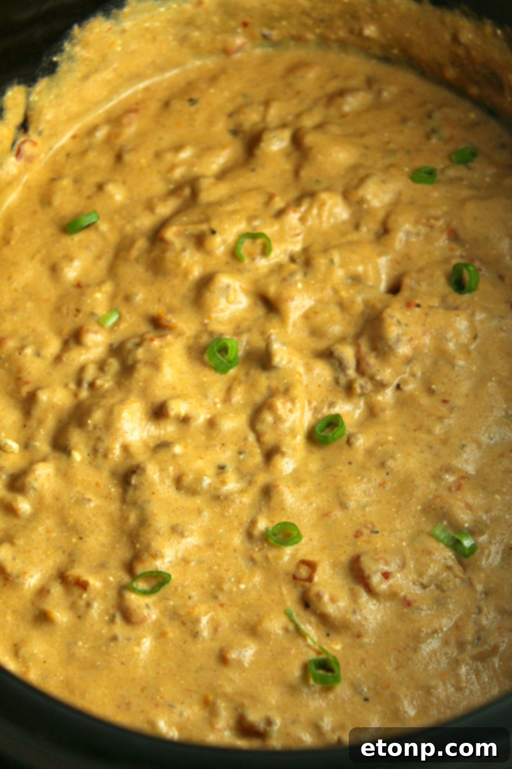 The Slow Cooker Taco Dip being served hot from the crock pot with a side of tortilla chips