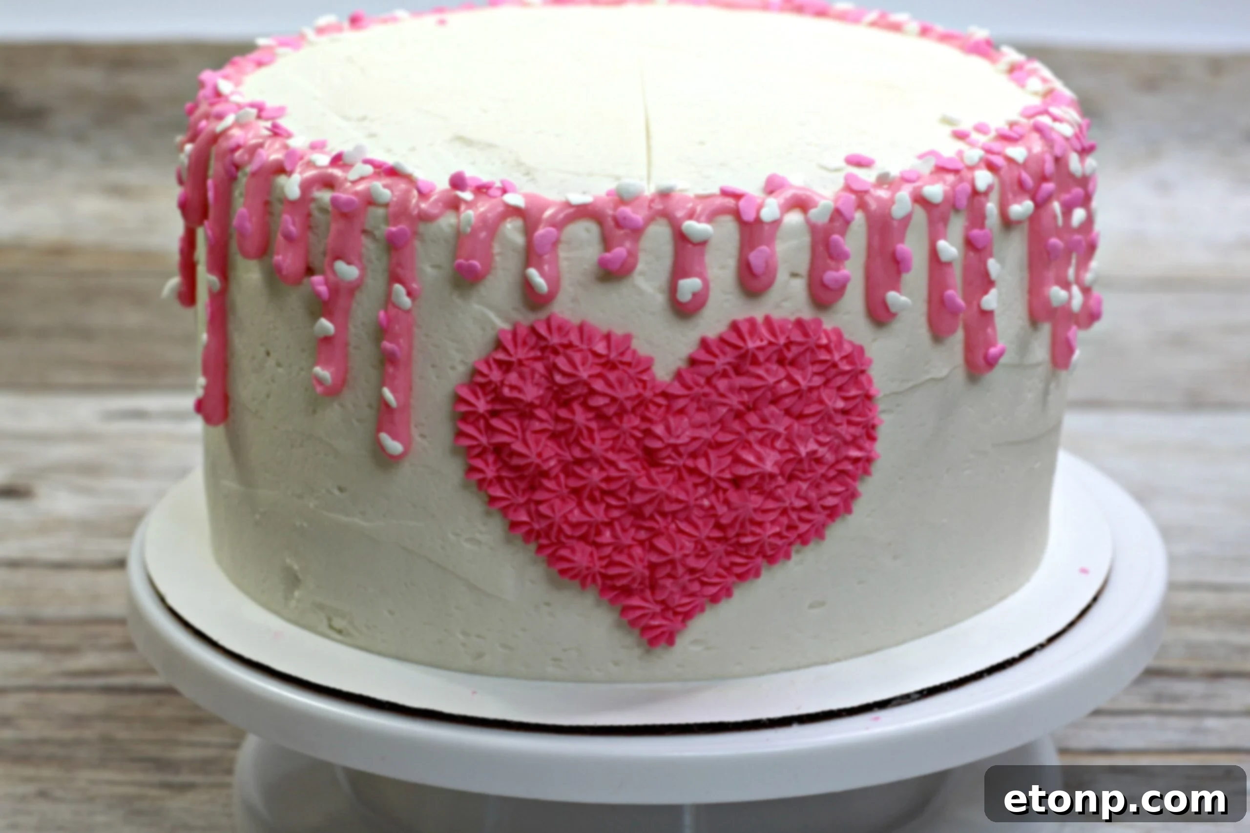 Close-up of a slice of Valentine's Day Love Cake, revealing moist pink and white marbled layers and creamy vanilla buttercream.