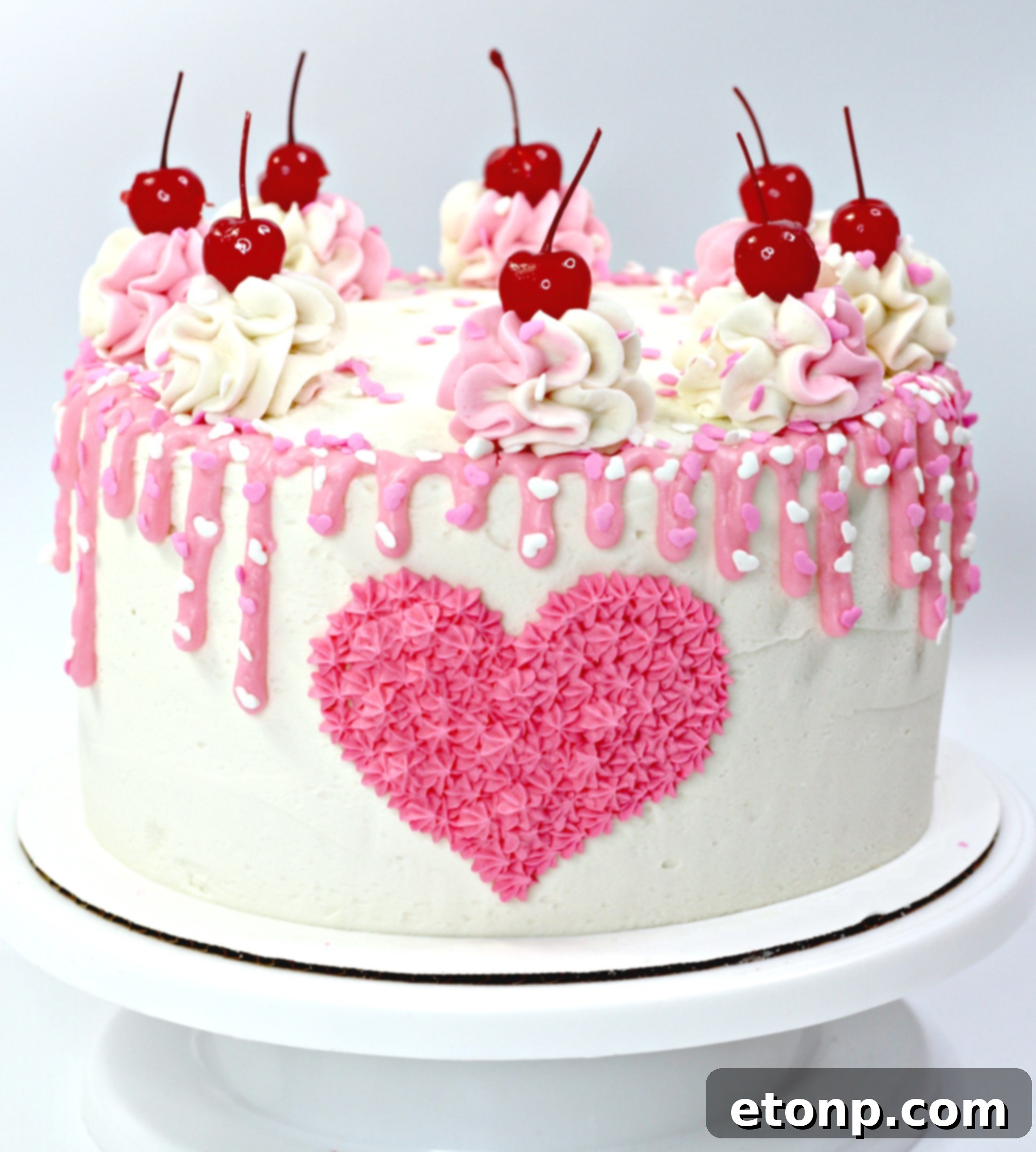 Overhead view of a beautifully decorated Valentine's Day Love Cake adorned with sprinkles and cherries.