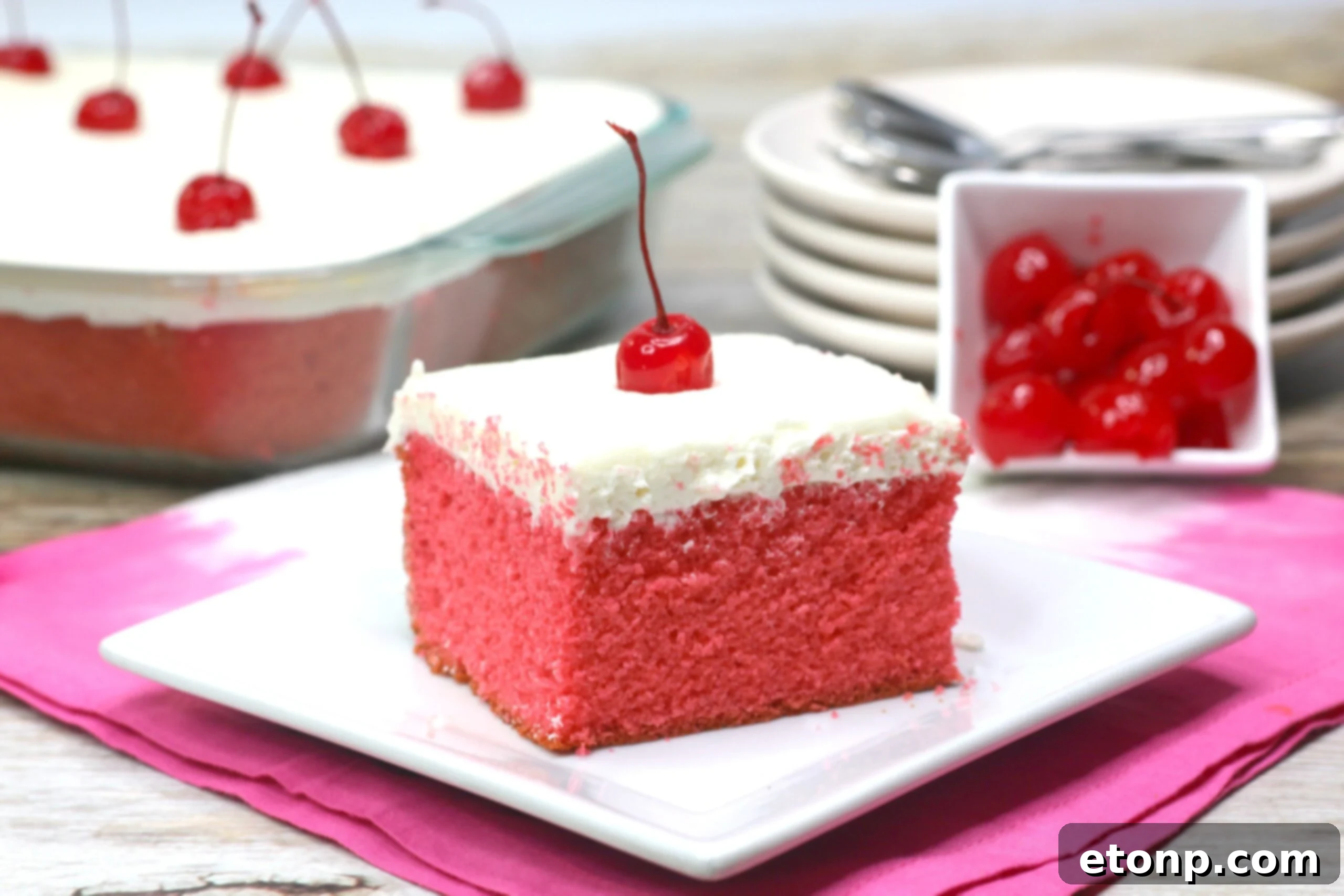 A beautifully decorated slice of Very Cherry Cake on a plate, showing the moist texture and the generous layer of vanilla buttercream.