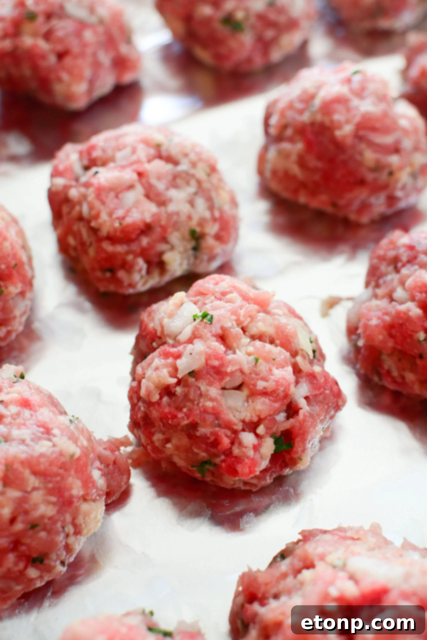 Grandma's Baked Italian Meatballs 3 A baking sheet filled with raw Italian meatball mixture rolled into balls, ready for the oven.