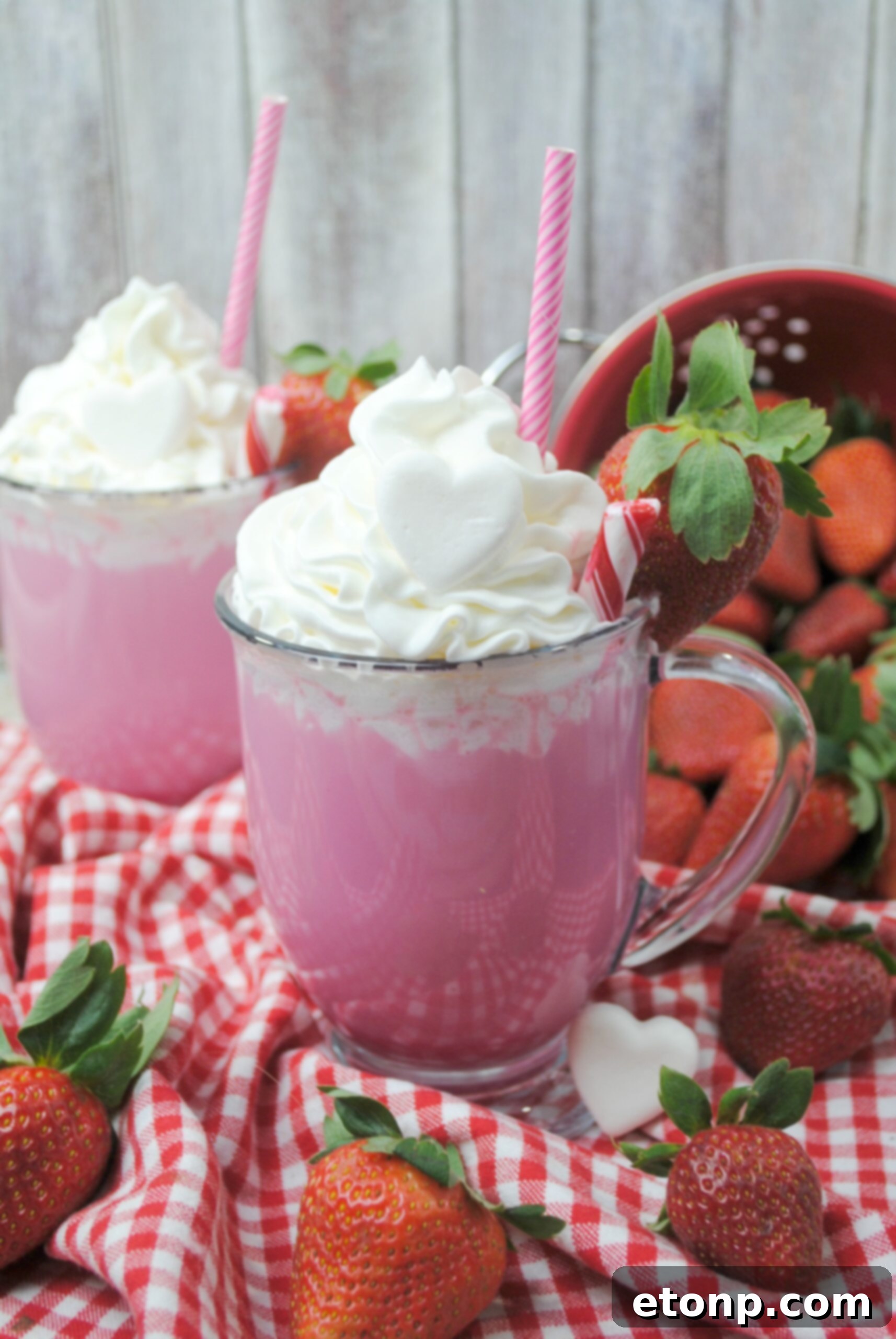 Close-up of a mug of Pink Velvet Hot Chocolate topped with fluffy whipped cream and a dusting of cocoa powder