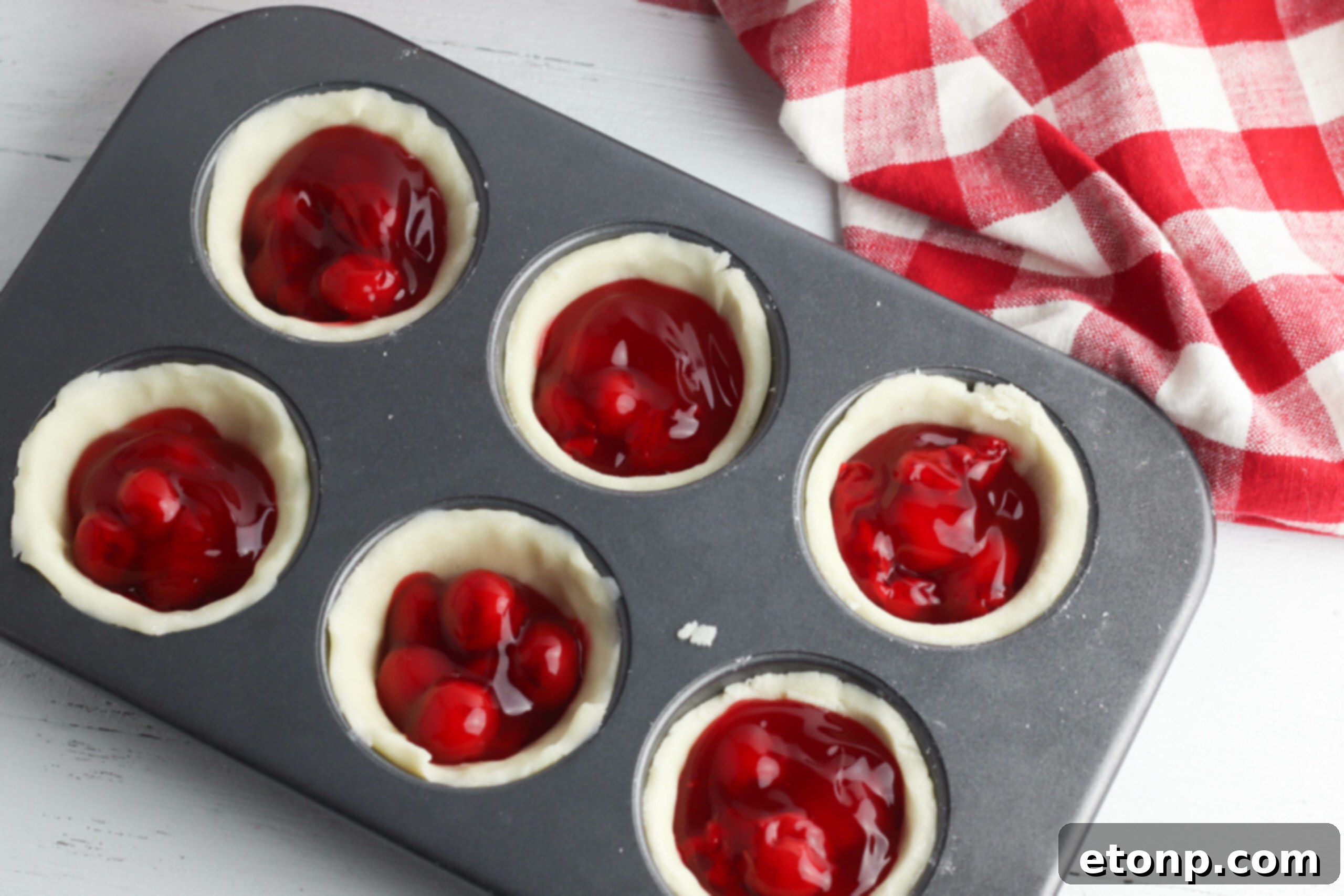 Two hands gently holding a freshly baked mini cherry pie, highlighting its individual serving size