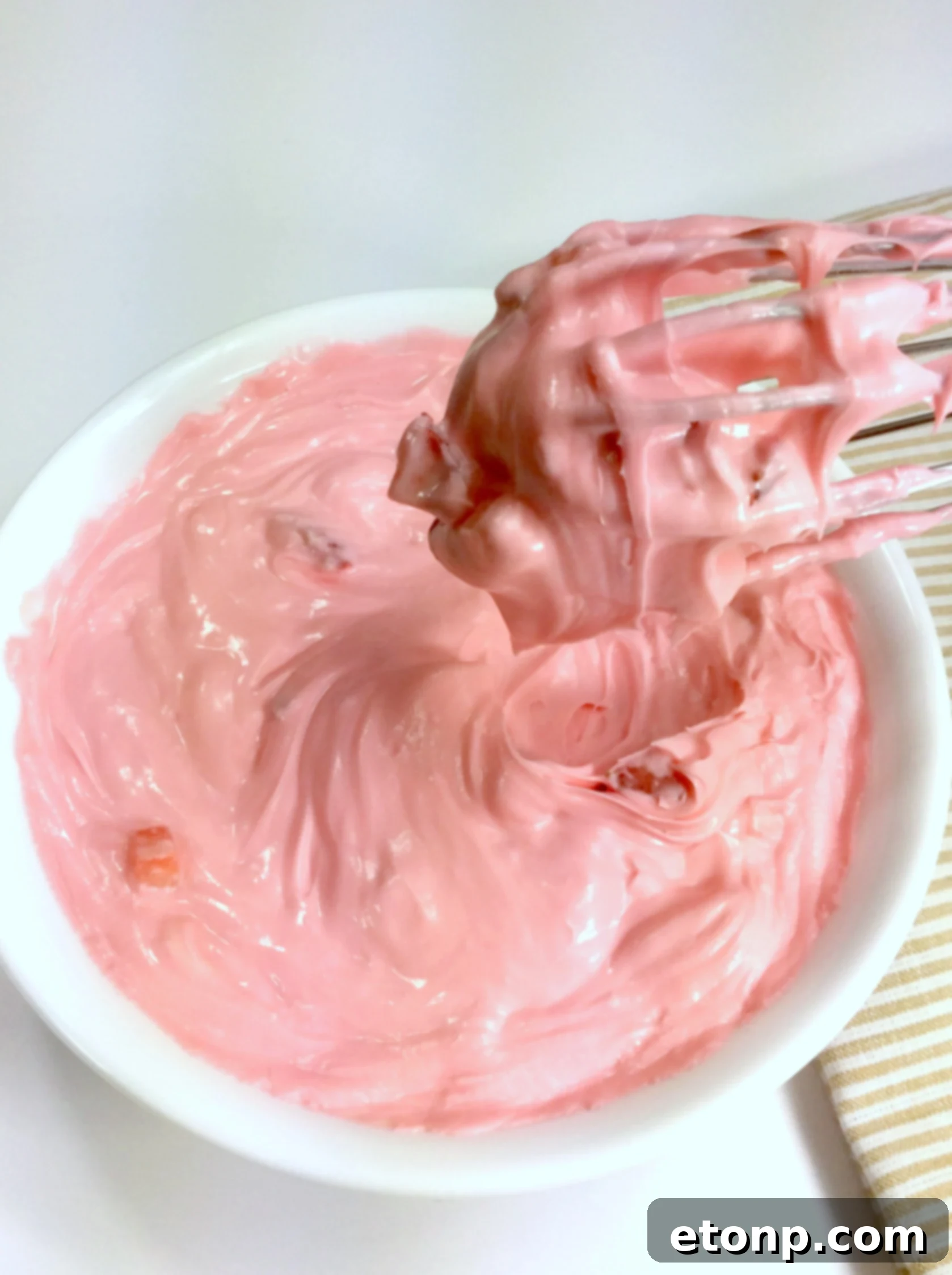 Close-up of fluffy strawberry buttercream frosting in a bowl.