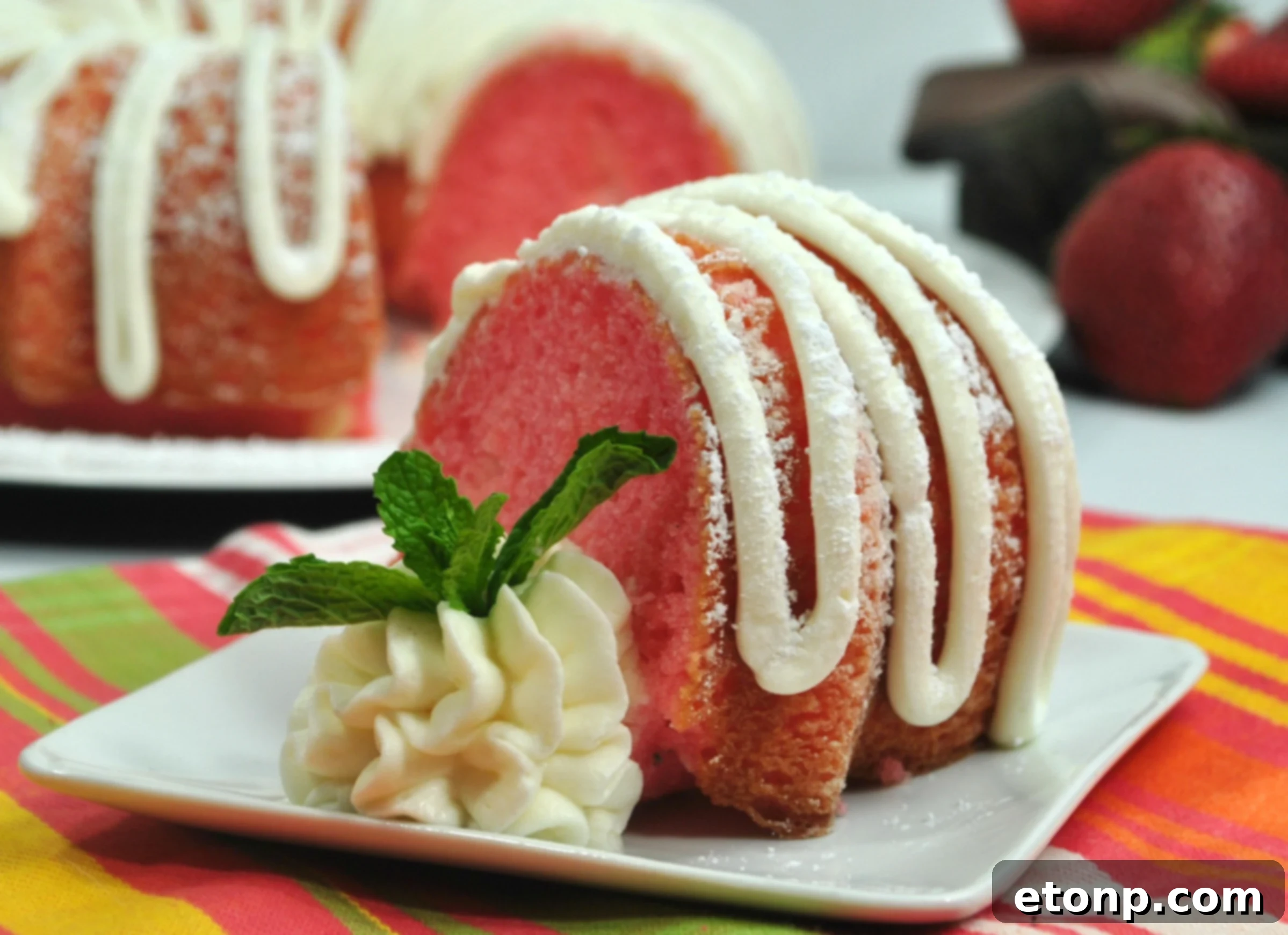 A close-up view of a slice of Strawberries & Cream Bundt Cake, revealing the moist crumb speckled with fresh strawberries and a peek of the creamy filling, ready to be enjoyed.