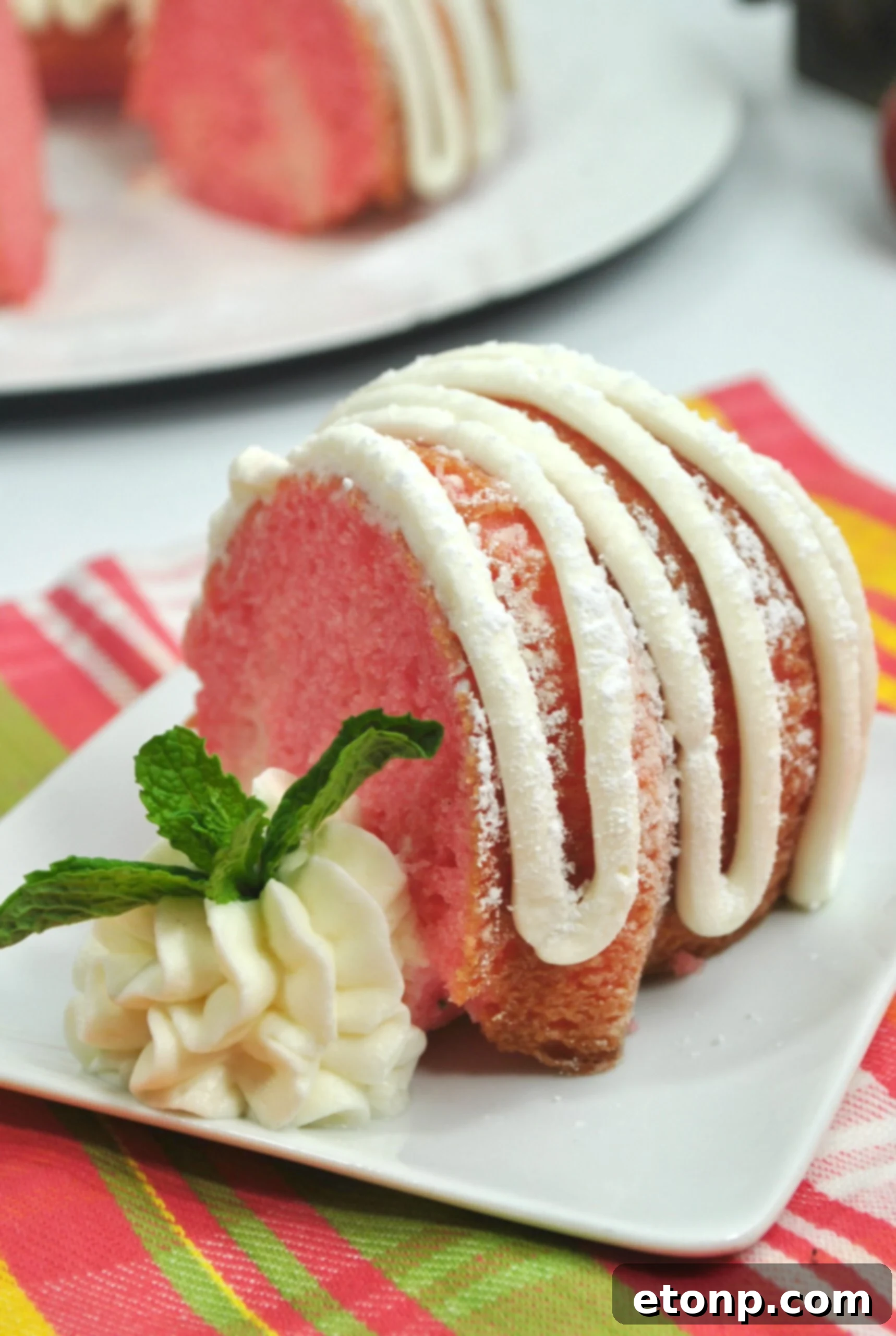 A close-up detail of the Strawberries & Cream Bundt Cake, highlighting the texture of the cake and the smooth, creamy frosting, making it look incredibly appetizing.
