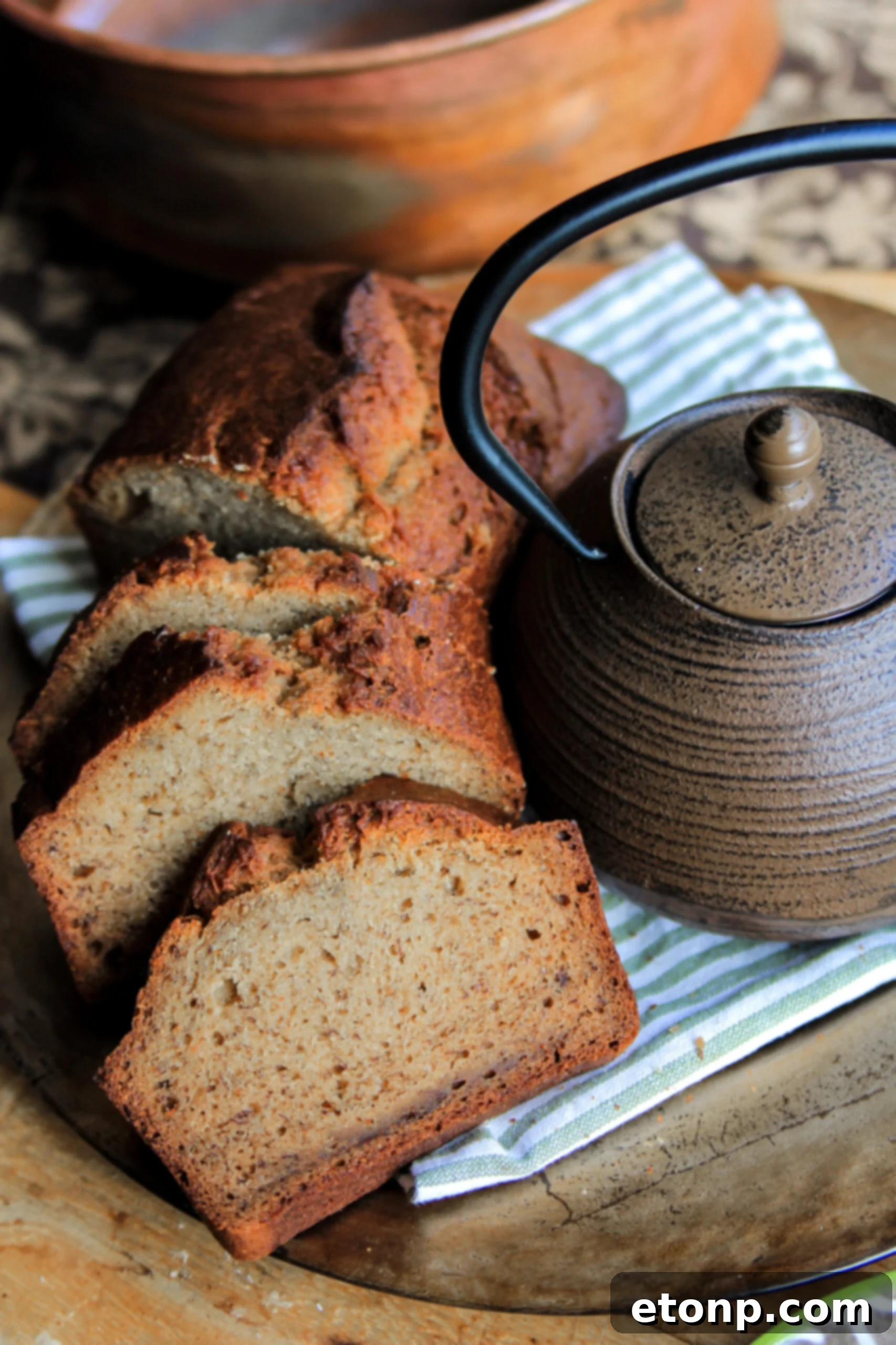 A perfectly baked loaf of moist banana bread, sliced and ready to serve, showcasing its golden brown crust and tender interior.