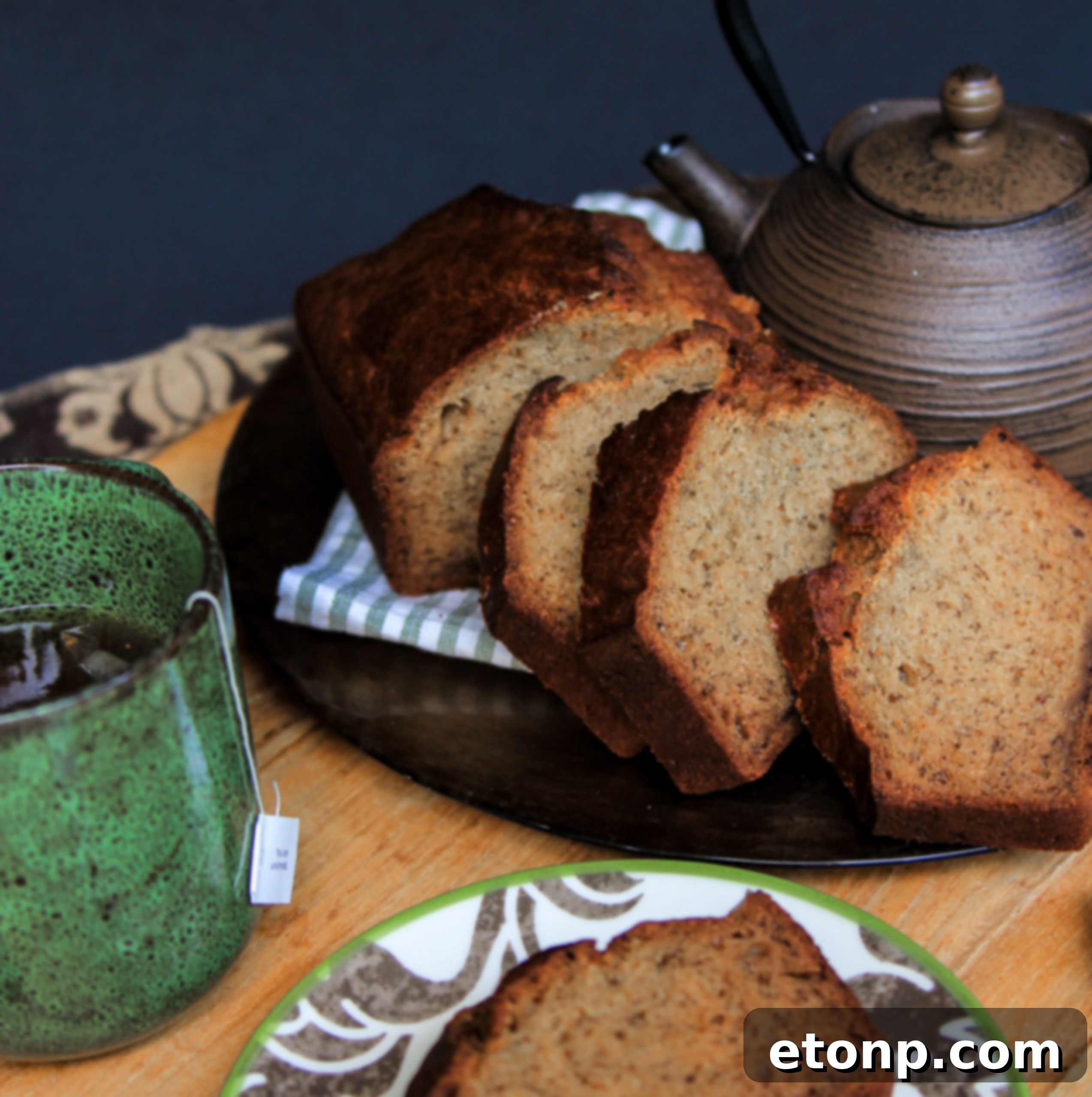A close-up shot of a thick slice of banana bread, perfectly toasted and spread with butter, placed on a white plate.